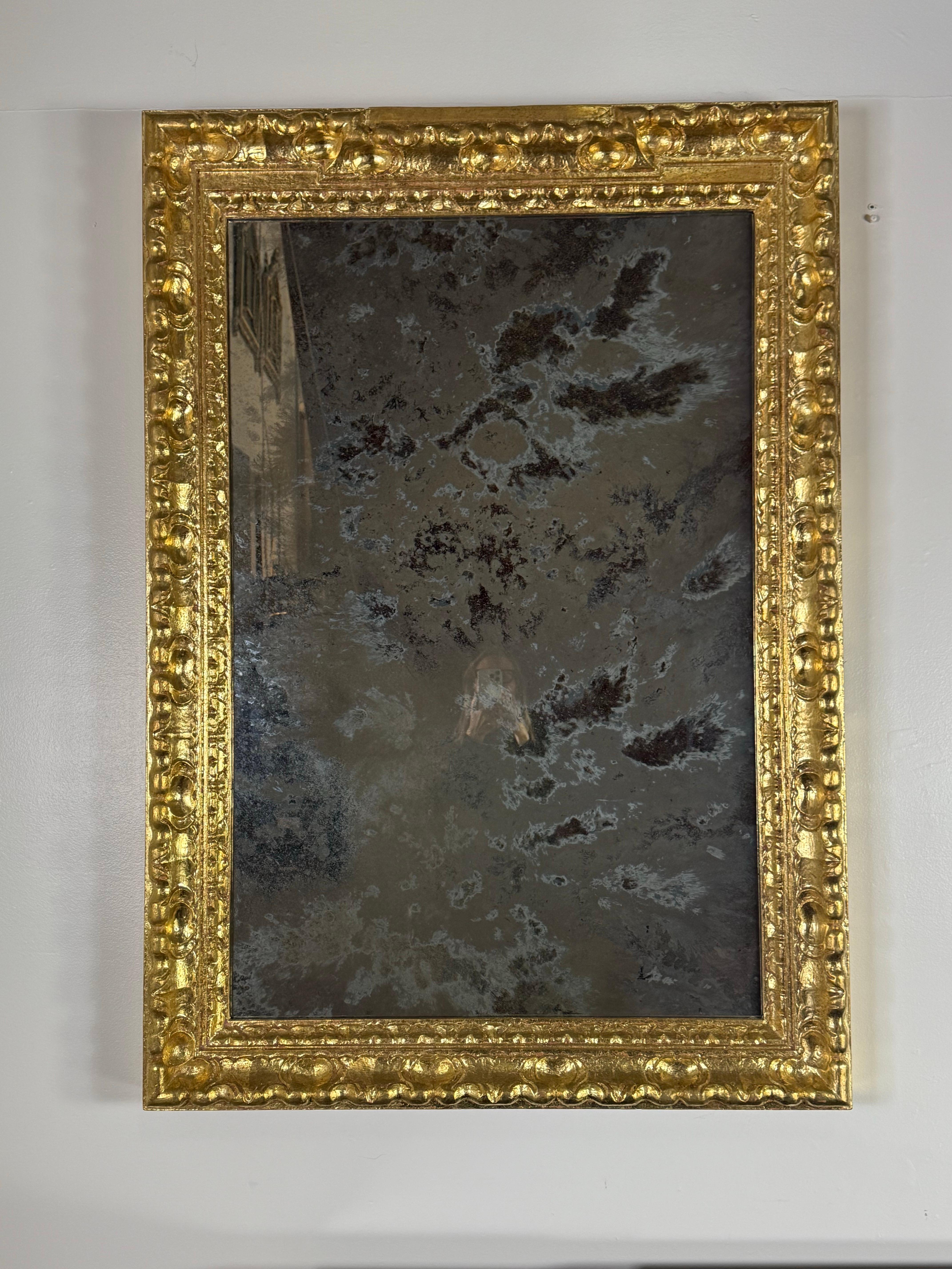 Un sorprendente specchio italiano in legno dorato con una lastra di vetro al mercurio riccamente patinata. La cornice è intagliata ad alto rilievo con motivi ondulati a fogliame e a volute, il tutto rifinito con una calda superficie dorata applicata