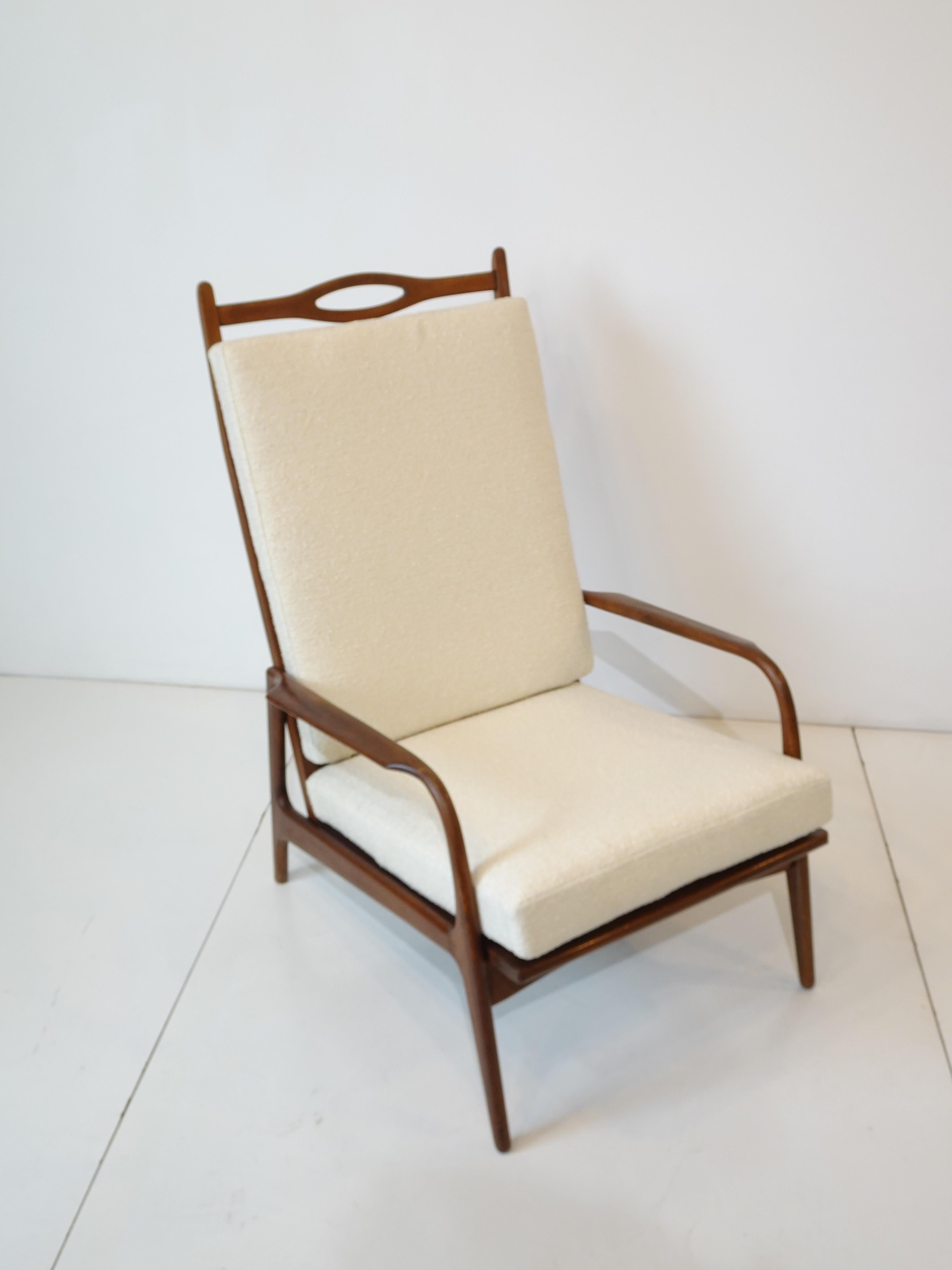A wonderful mid century walnut framed lounge chair with nicely designed slim arms and sculptural back having two loose cushions covered in cream tone Boucle fabric . A piece of furniture that's art and is super comfortable and makes a statement just