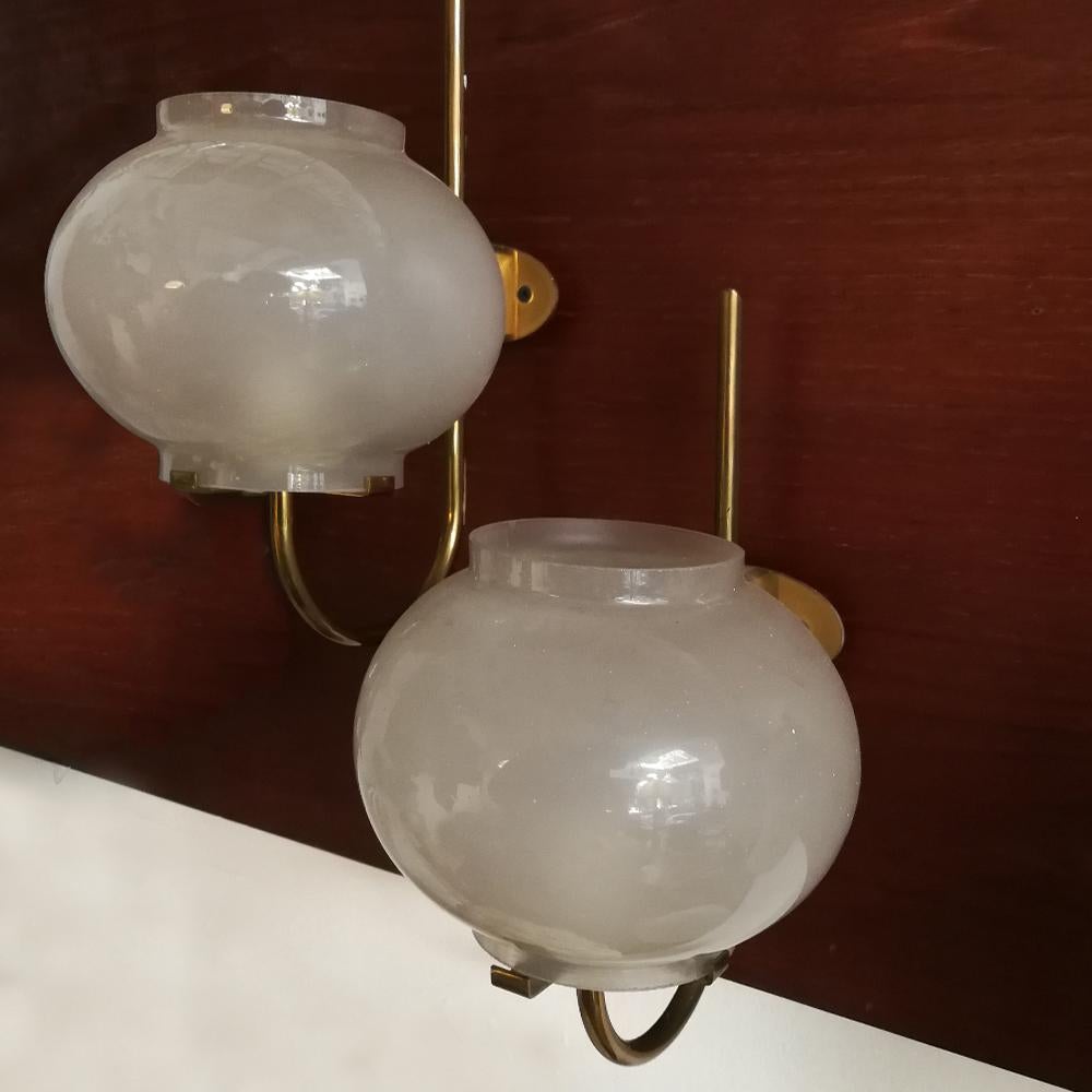 Italian glass and brass appliques by Tito Agnoli for Oluce, 1960s
Classic pair of Oluce Italian 1960s single shade wall sconces by Tito Agnoli. The structure is in brass and carry a blown patinated glass on it, opened from both sides, creating a