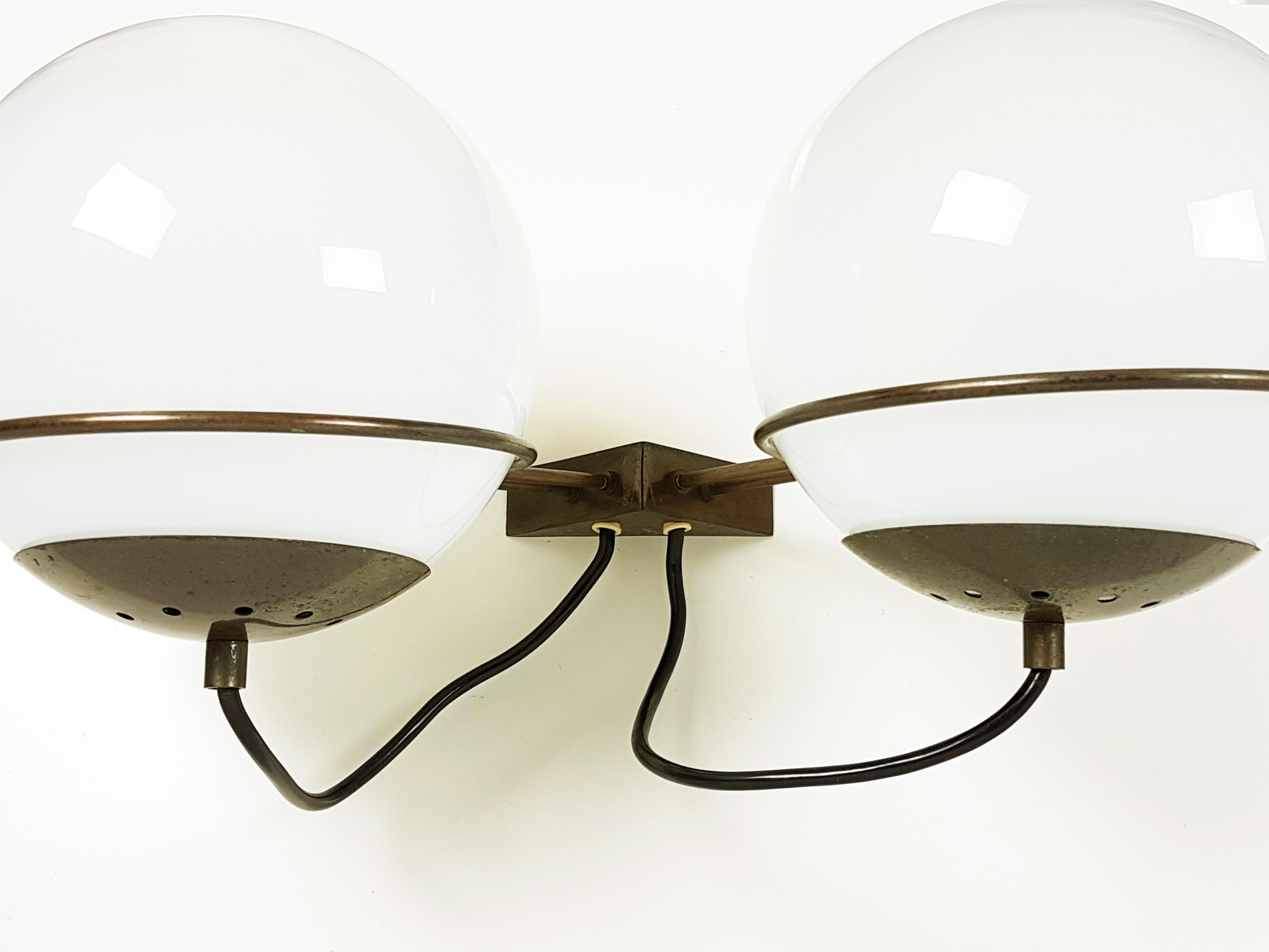 This pair of two-light sconces (mod. B519) was produced in Italy, circa 1960s by Candle. They are made from a oxidated brass structure with two hand blown spherical faded glass shades. Their design resemble similar items from Arteluce production.
