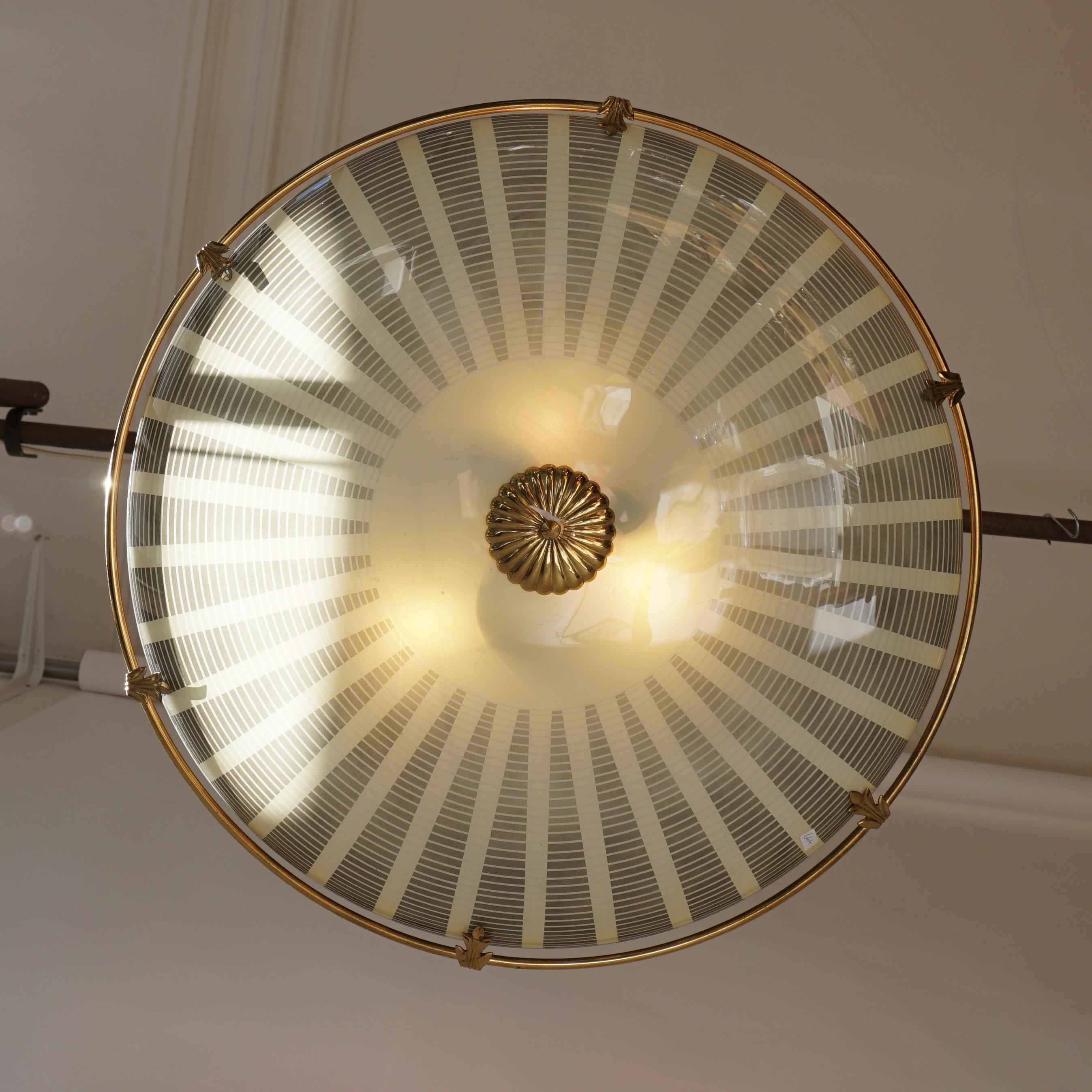 This ceiling lamp was produced in Italy in the late 1950s. It is made from a brass frame with a glass shade.It can be used as wall lamp as well. 

The light requires three single E27 screw fit lightbulbs (60Watt max.) LED compatible.
Diameter 63