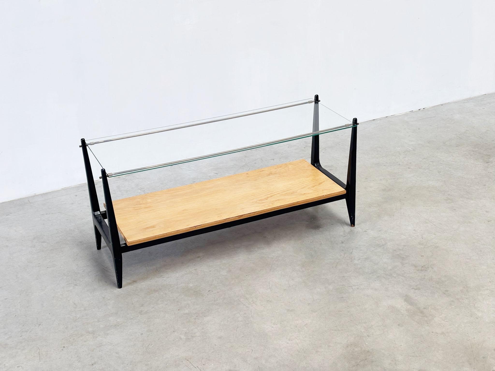 Elégante table basse italienne de Milan des années 1960, mettant en valeur les lignes raffinées du design italien du milieu du siècle.
Doté d'un tout nouveau plateau en verre, d'une étagère en chêne et d'un élégant cadre laqué noir.
Une pièce