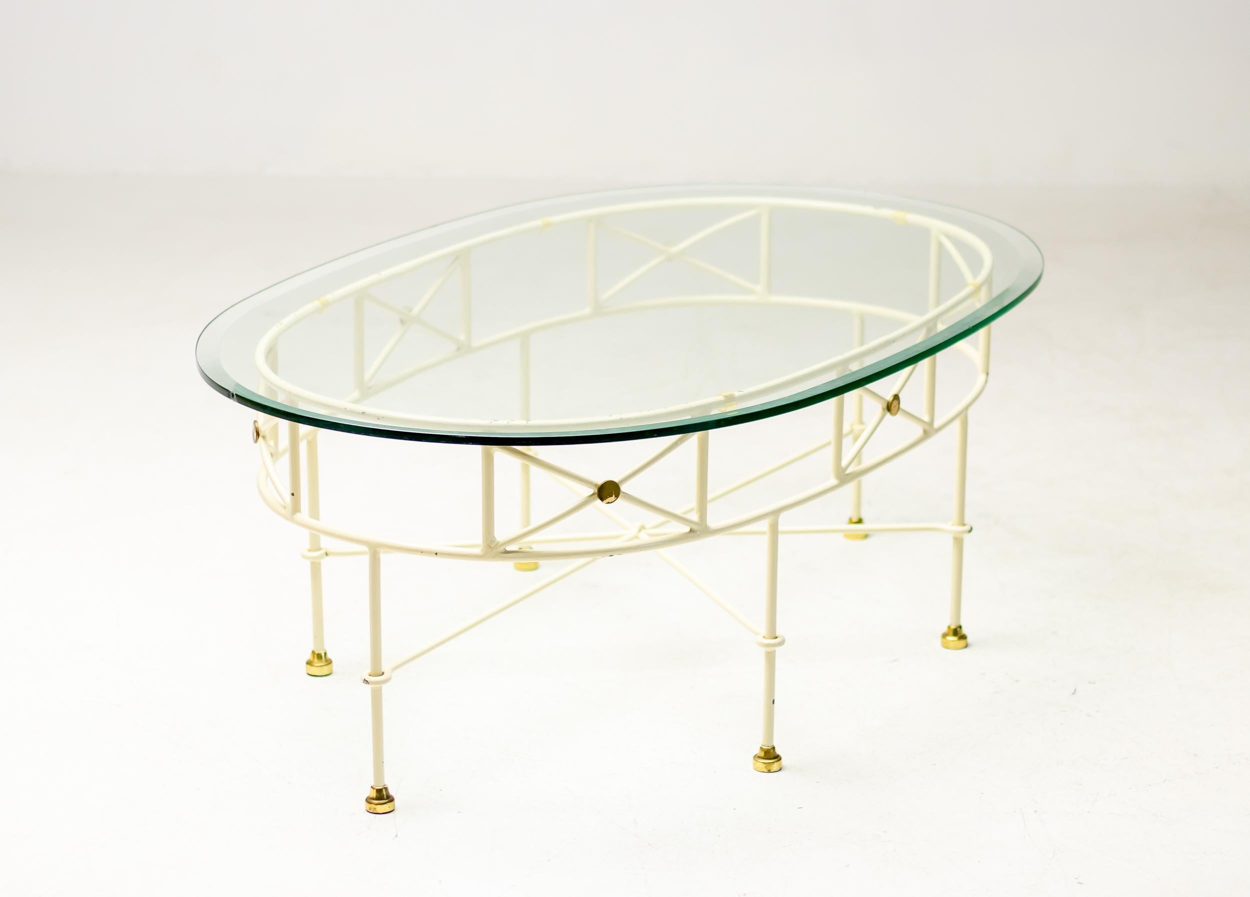 Elegant Mid-Century Modern Italian oval glass top coffee table.
White enameled steel base with brass feet and bevelled crystal glass top.
Beautiful presence.