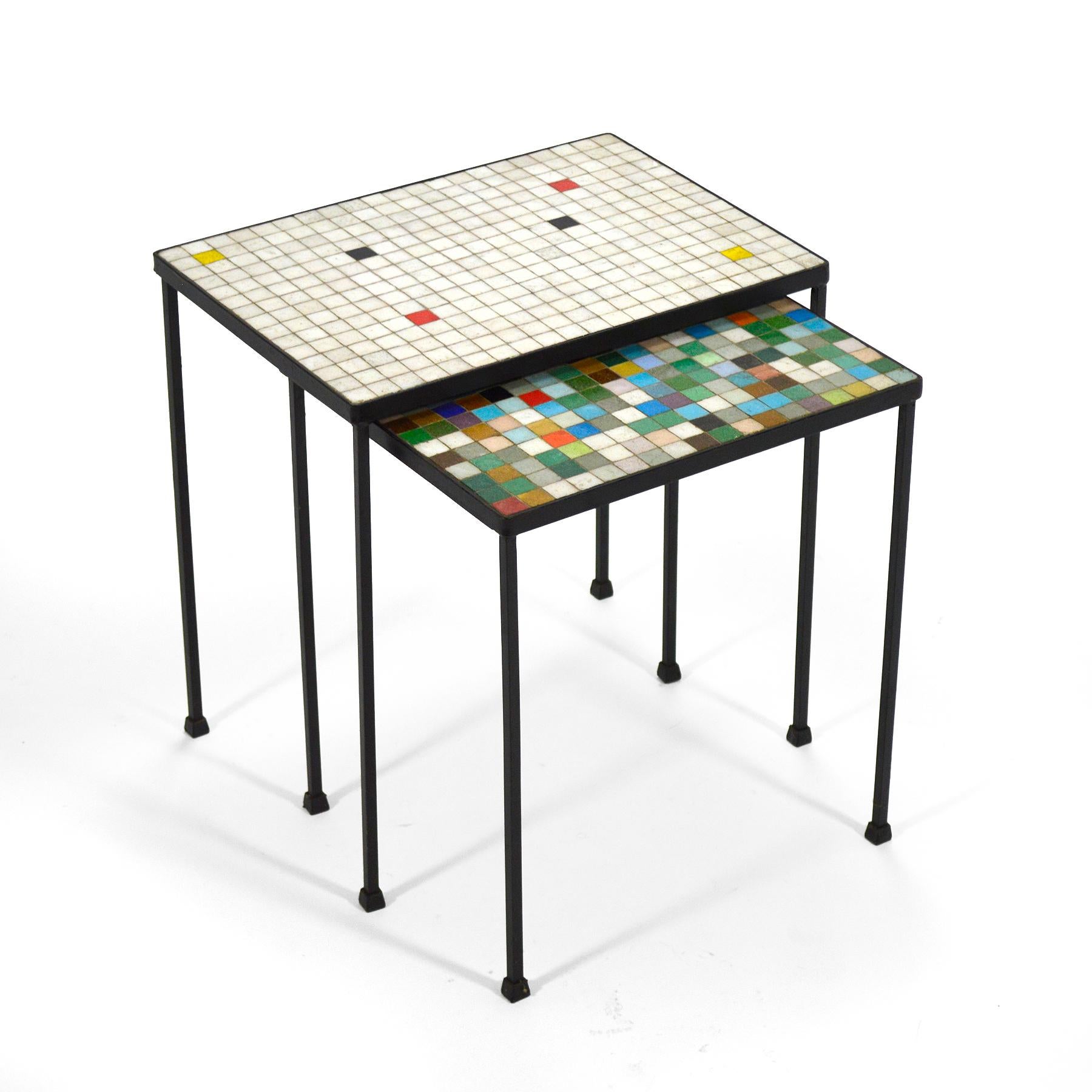 This pair of pretty nesting tables have bases of wrought iron which support tops of Italian glass tiles. The larger table is mostly white, with small color accents, while the smaller table is a colorful explosion. They can be used in tandem or
