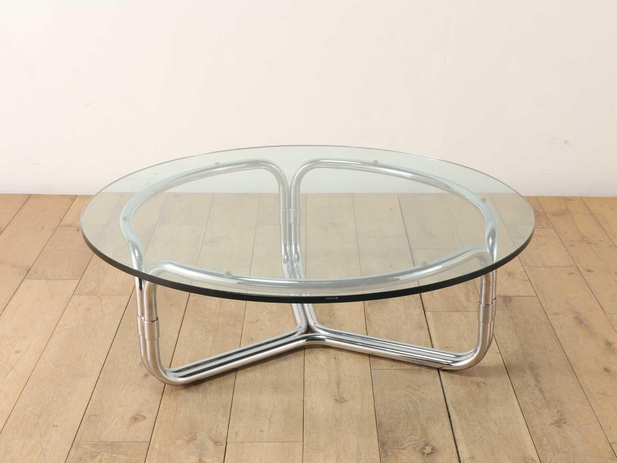 Dieser Couchtisch zeichnet sich durch sein unverwechselbares Design aus, das durch die einzigartig geschwungenen Chrombeine hervorgehoben wird, die eine kühne und doch raffinierte Silhouette bilden. Das reflektierende Metall verleiht dem Stück einen