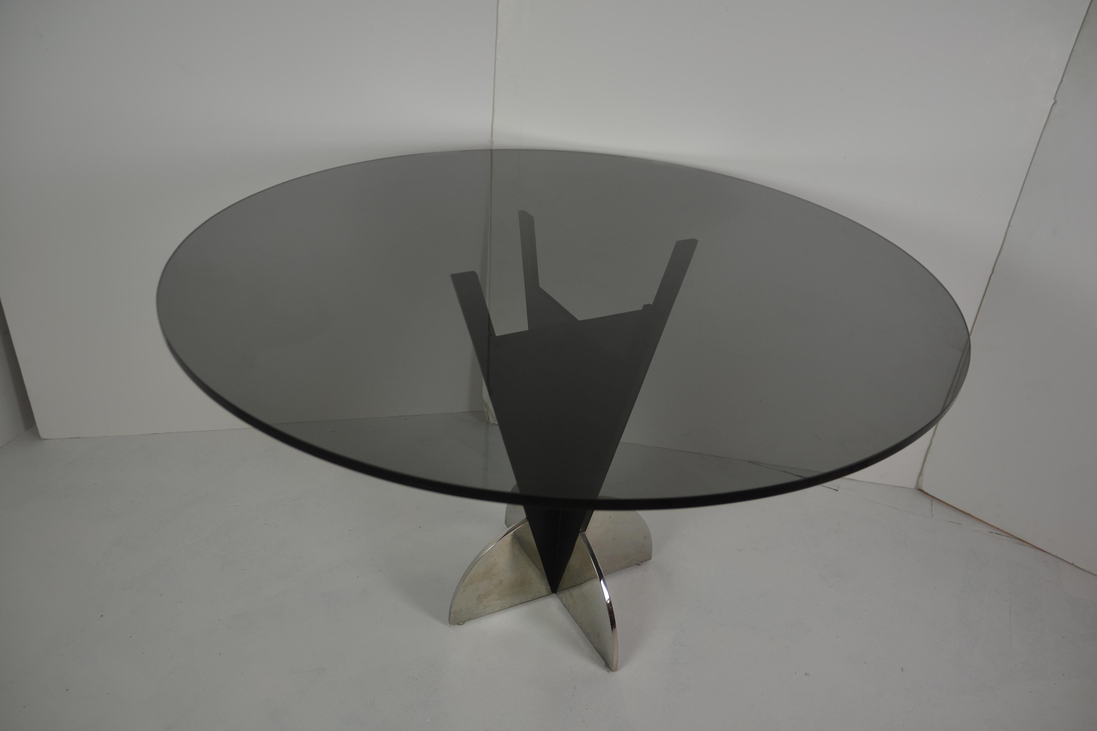 Table italienne de forme ronde en verre fumé de qualité supérieure. La base est en métal massif et chromé.