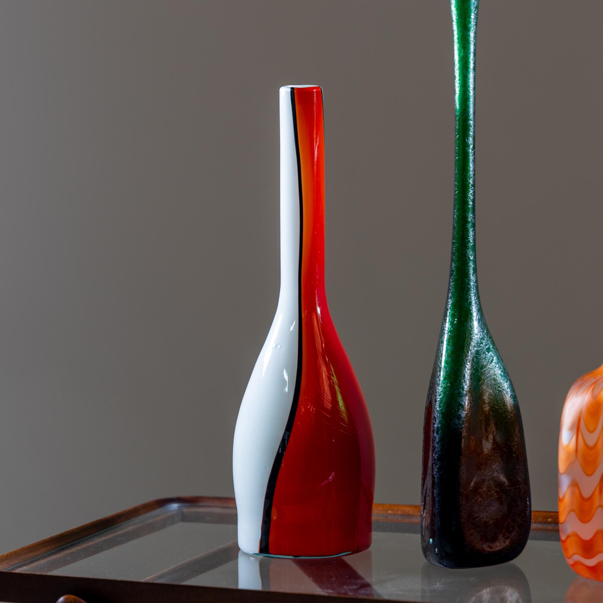 Three Italian vases made of glass in red and orange (Murano) and green (Seguso) with different decorations and basic shapes.