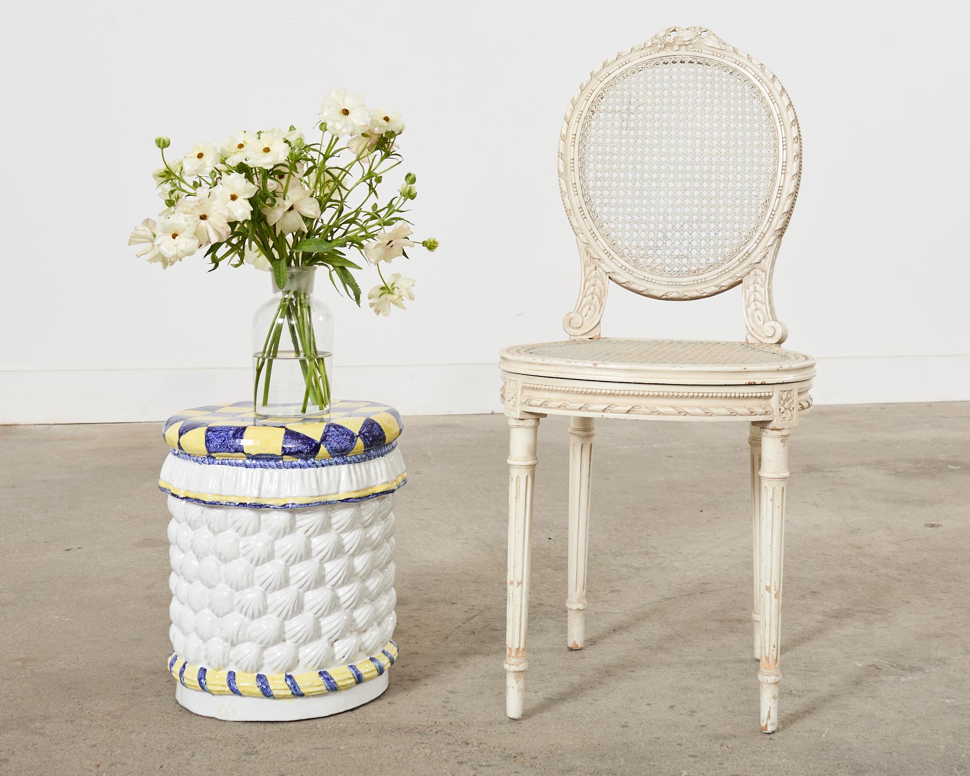 Whimsical 20th century Italian glazed ceramic garden stool or drinks table featuring a trompe l'oeil seashell veneered form. The top has a harlequin diamond pattern painted in citron yellow and blue. The seat has a skirted ruffle border on the top