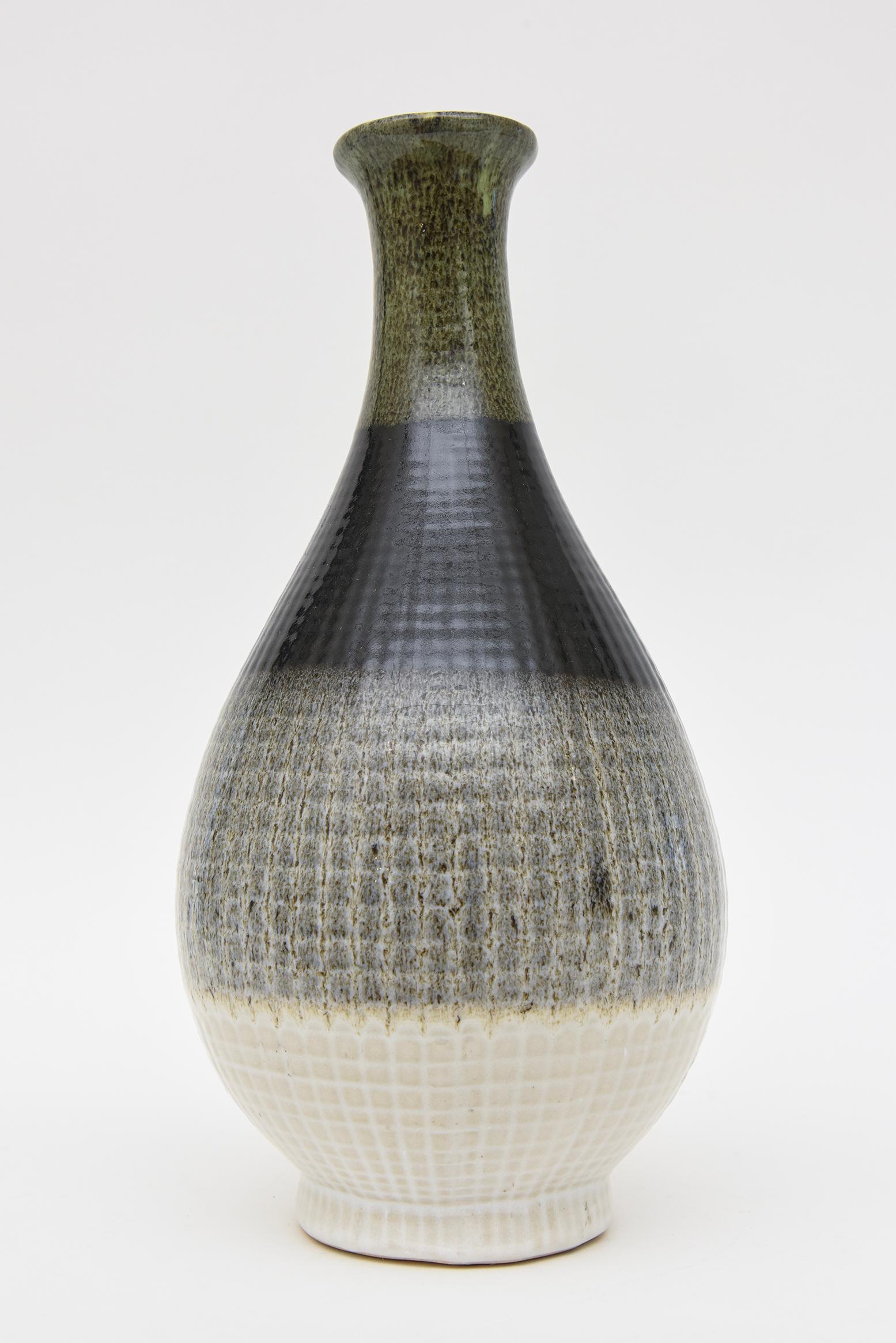 Cette grande bouteille ou récipient en céramique italienne émaillée est dans le style de Fantoni et présente des éléments de larges bandes de couleurs et de motifs. Les couleurs vont du vert au noir en passant par le charbon de bois et le blanc