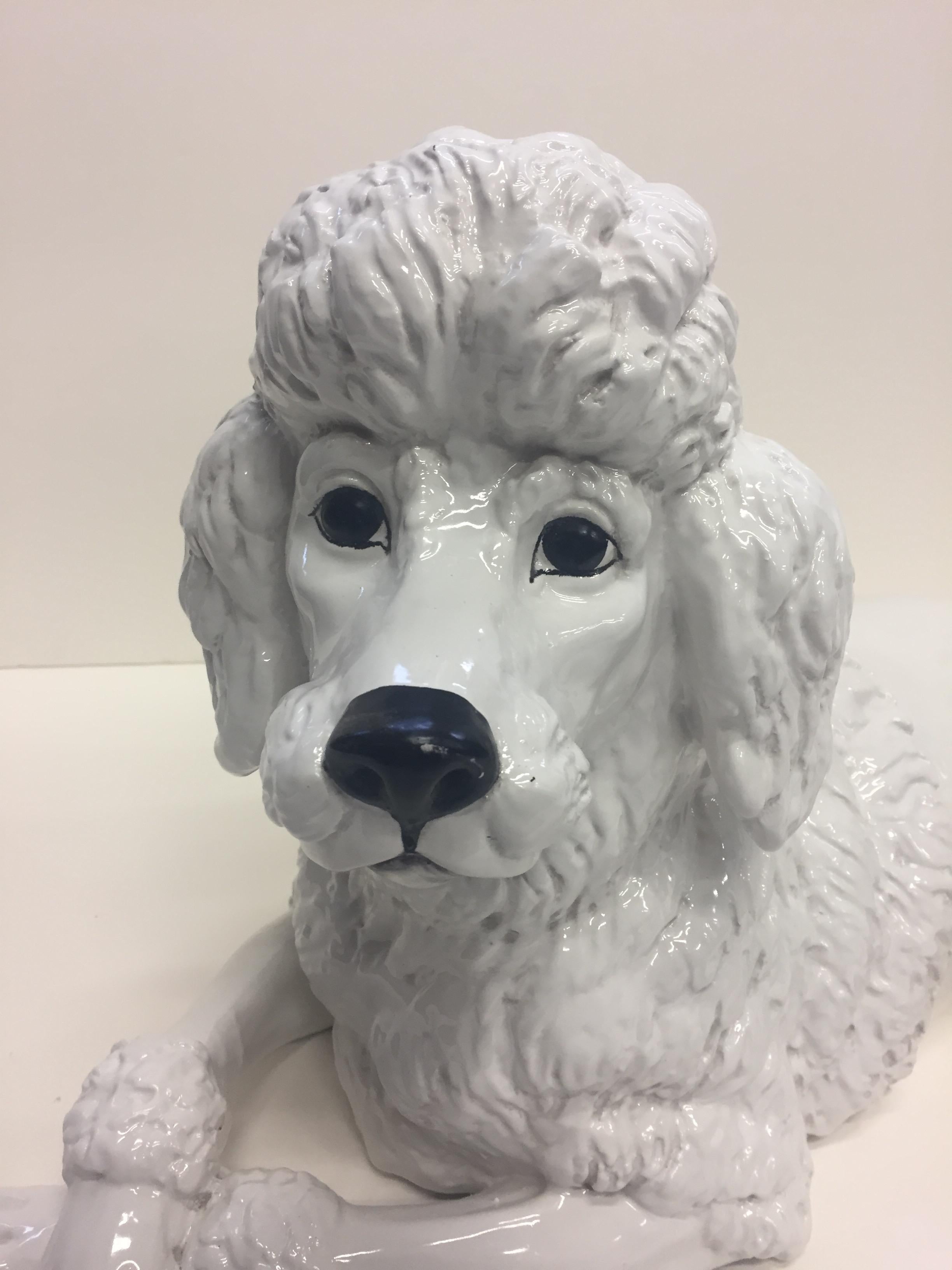 A poodle lovers dream glazed terracotta sculpture of an adorable pup with crossed front paws. 
  