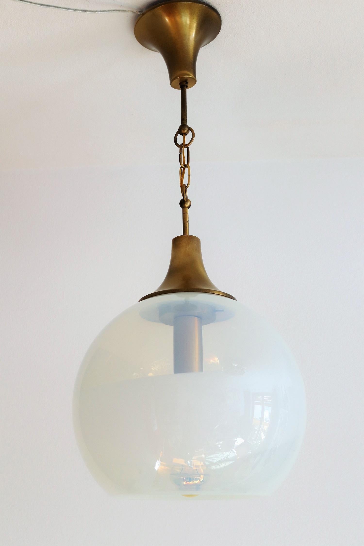 Gorgeous pendant lamp of Italian Production with magnificent opalescent glass globe and brass details.
Made in Italy, 1970s.
The glass globe of light creamy opalescent color has a large white stripe all around and gives together with the brass