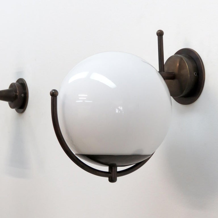 Wonderful Italian wall lights with a large glass globe perched on a patinaed brass framework, wired for US standards or European standards (110v/240v), one E27 socket, max. wattage 75w, bulb provided as a onetime courtesy.