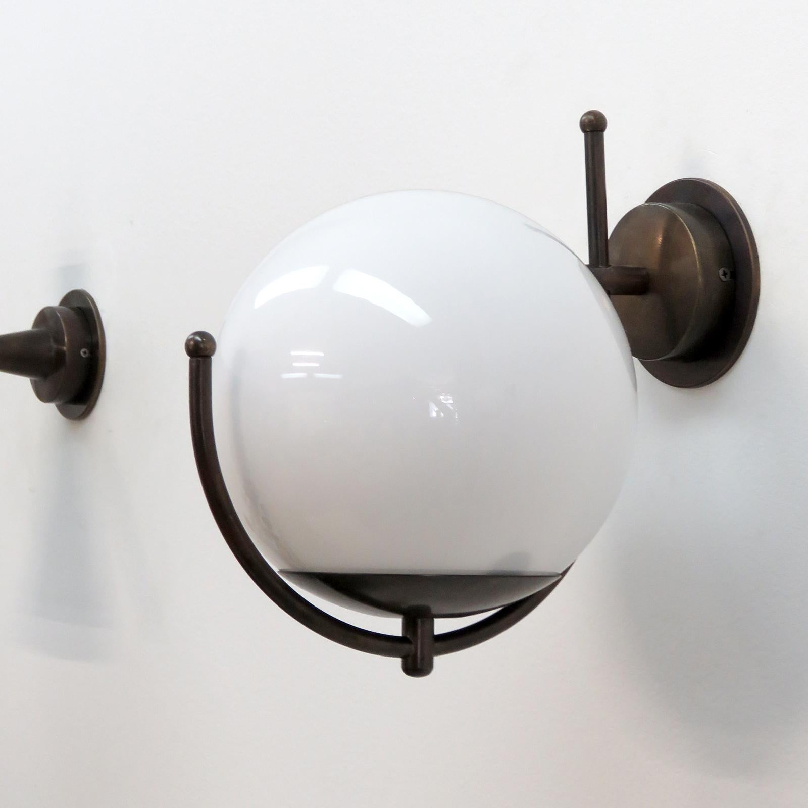 Wonderful Italian wall lights with a large glass globe perched on a patinaed brass framework, wired for US standards or European standards (110v/240v), one E27 socket, max. wattage 75w, bulb provided as a onetime courtesy. 

Priced individually.