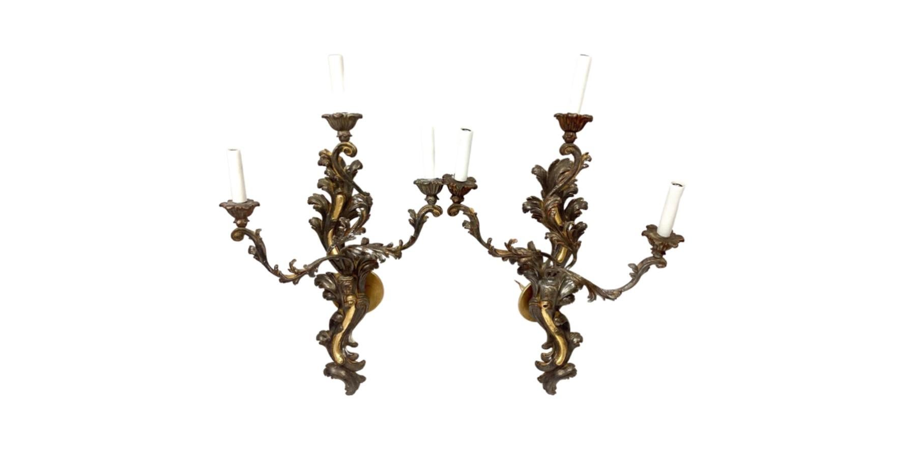 Decorative pair of large ornate Italian wall lights/sconces. Contrasting Gold and Silver giltwood and painted toleware scrolling on triple arm lights. Fully rewired. Stamped with 