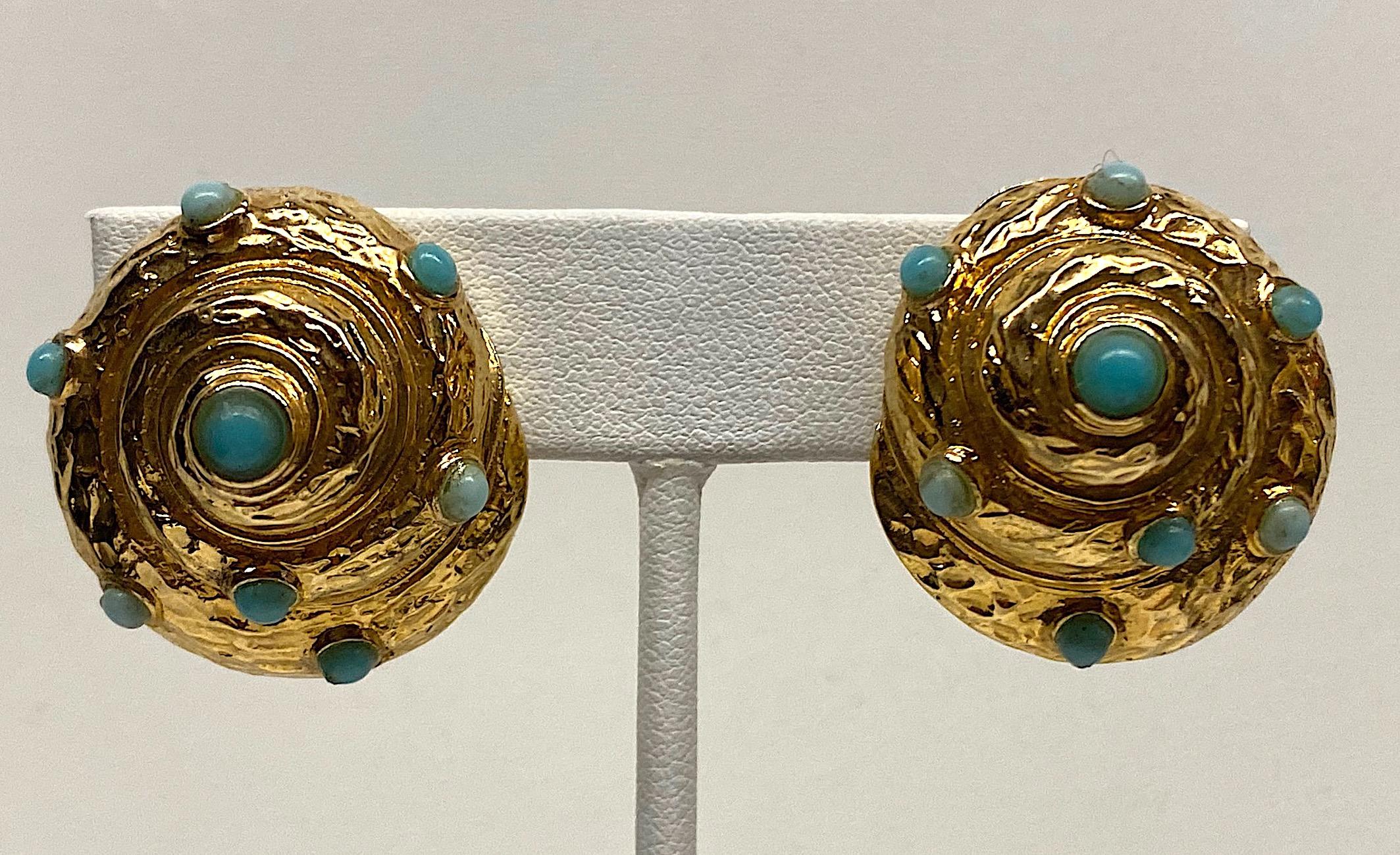 A nicely carved and detailed pair of spiral sea shell earrings circa 1980. The earrings are gold plate and set with two shades of faux turquoise cabochons. Each clip earring measures 1 inches wide, 1.13 inches tall and .5 of an inch high / deep not