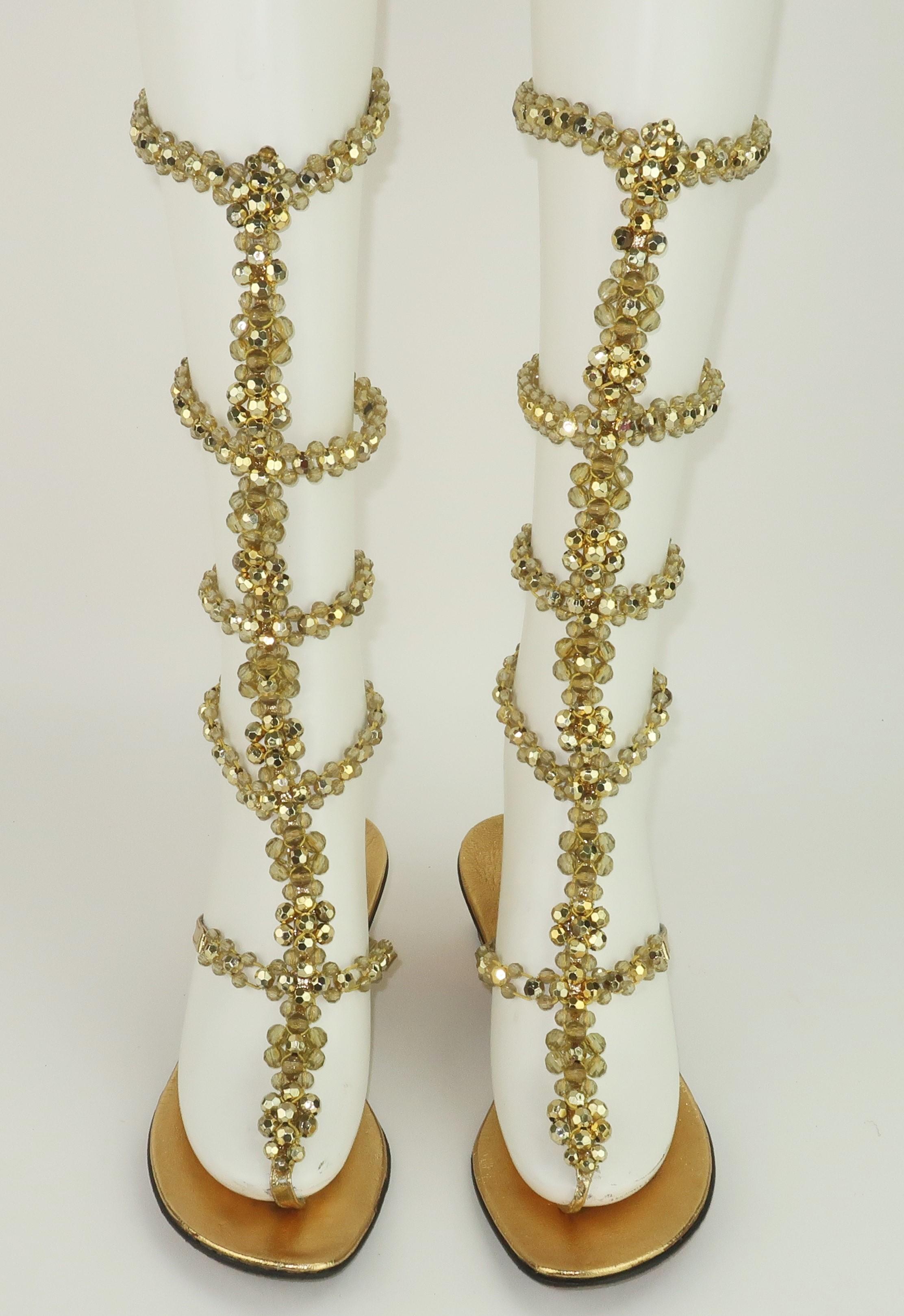 Goldener Glamour im Gladiatorenstil! Italienische DeMura-Sandalen aus den 1960er Jahren mit Ledersohle und einem Obermaterial aus goldenem Vinyl und elastischen, facettierten Goldperlen.  Die Sandalen haben eine Zehenstegkonstruktion und 5 Reihen