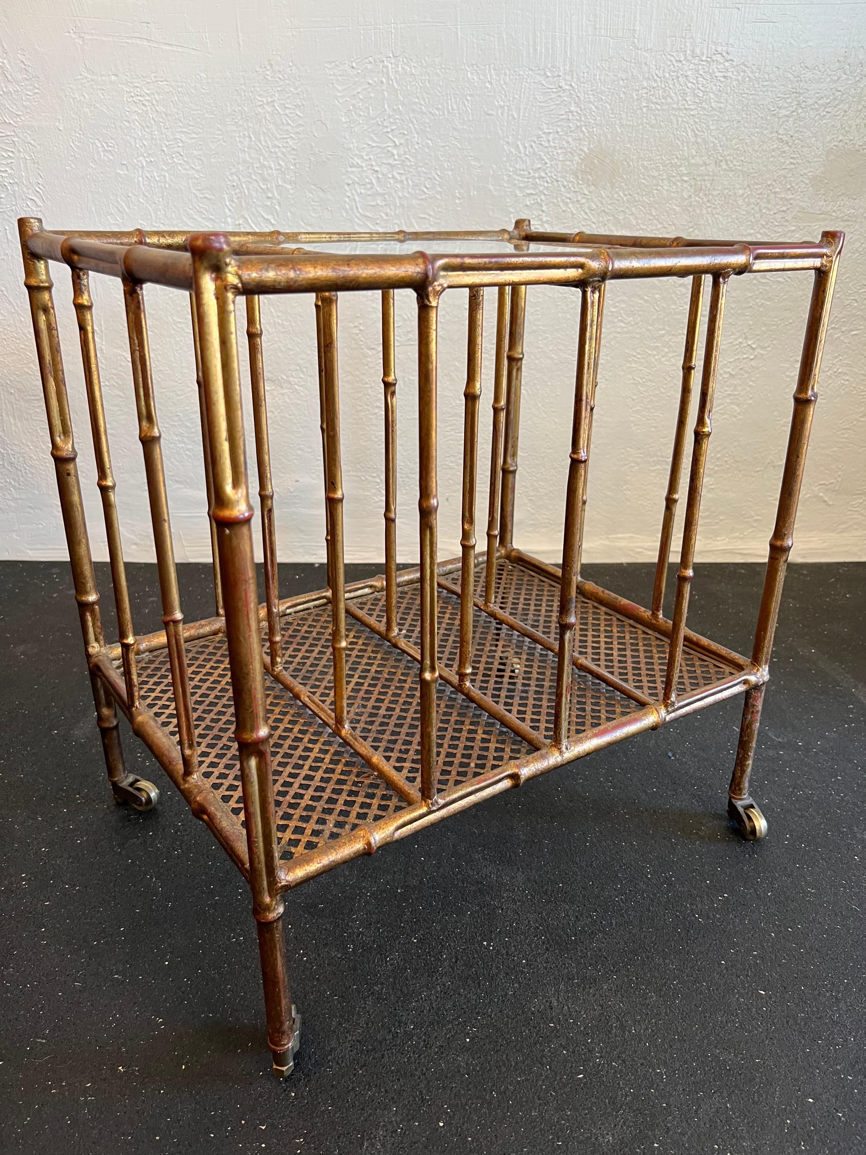 Italian gold gilded faux bamboo magazine rack table. Table is on solid brass castors for easy placement. No chips or cracks to glass insert but does show signs of wear. 

Would work well in a variety of interiors such as modern, mid century