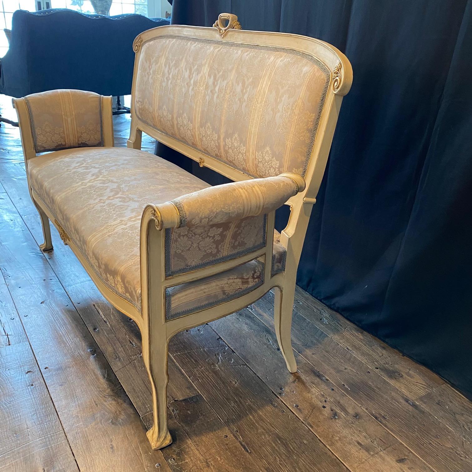 Lovely and elegant Art Nouveau Italian sofa, loveseat or settee painted neutral off white and gold, with beautiful original muted striped damask fabric. Can be sold separately; part of a 10-piece early 20th century Art Nouveau complete original