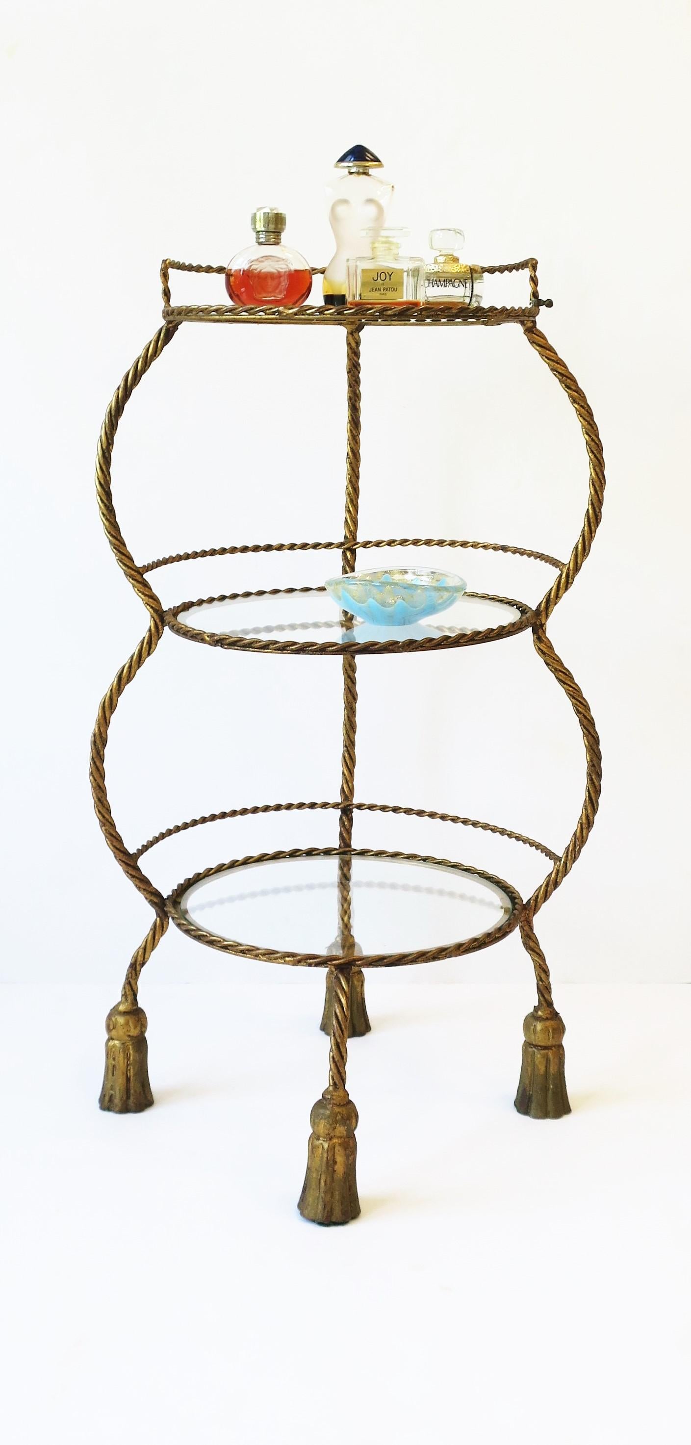 An Italian gold gilt metal tole étagère storage or display piece with rope and tassel design, circa mid-20th century, 1950s, Italy. Piece is documented/marked with metal tag reading 