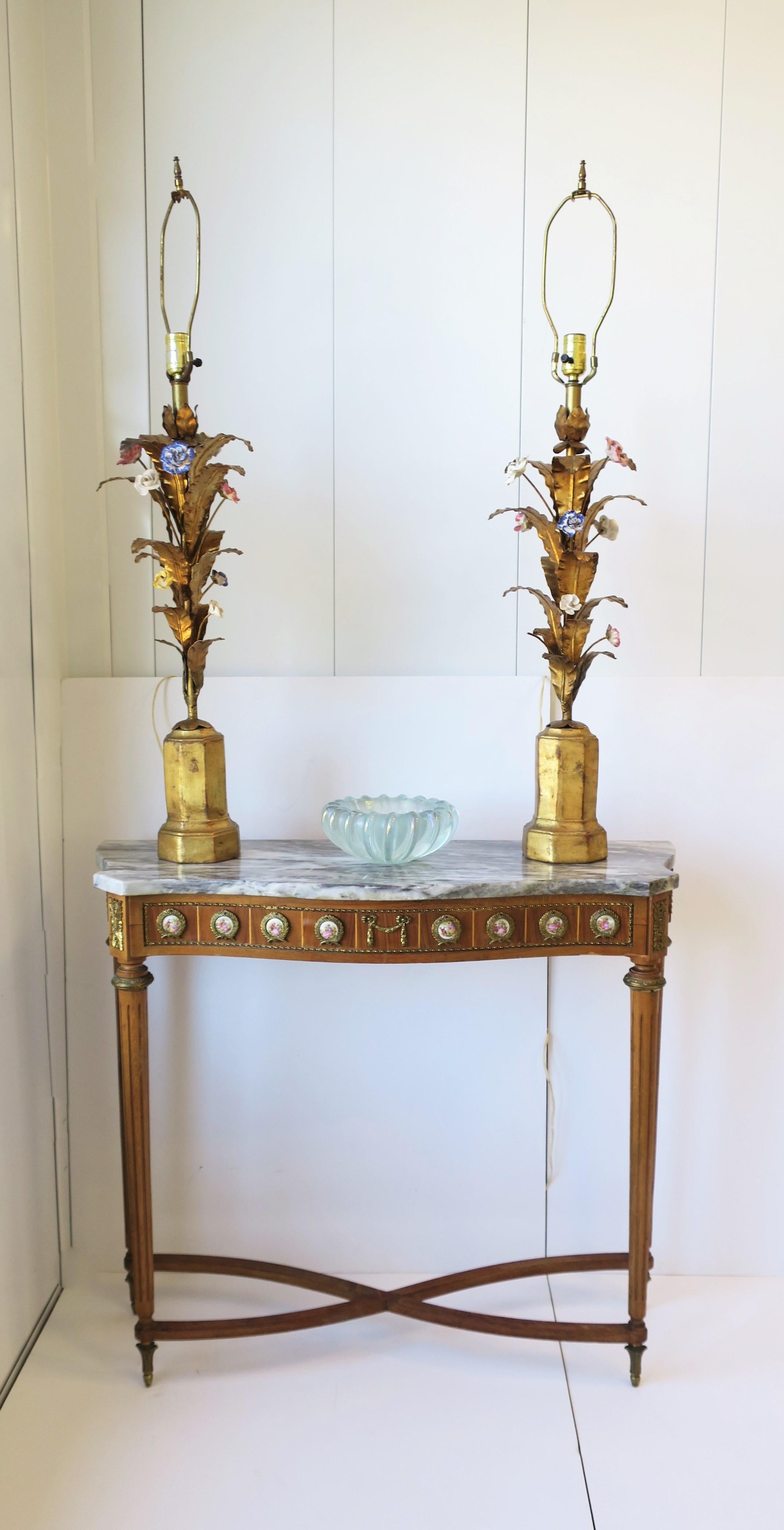 A beautiful pair of tall Italian gold gilt tole leaf and porcelain glazed flower table lamps, circa mid-20th century, 1960s, Italy. Bases are gold gilt covered terracotta with an octagonal shape. Leaves are gold gilt metal, and flowers are handmade