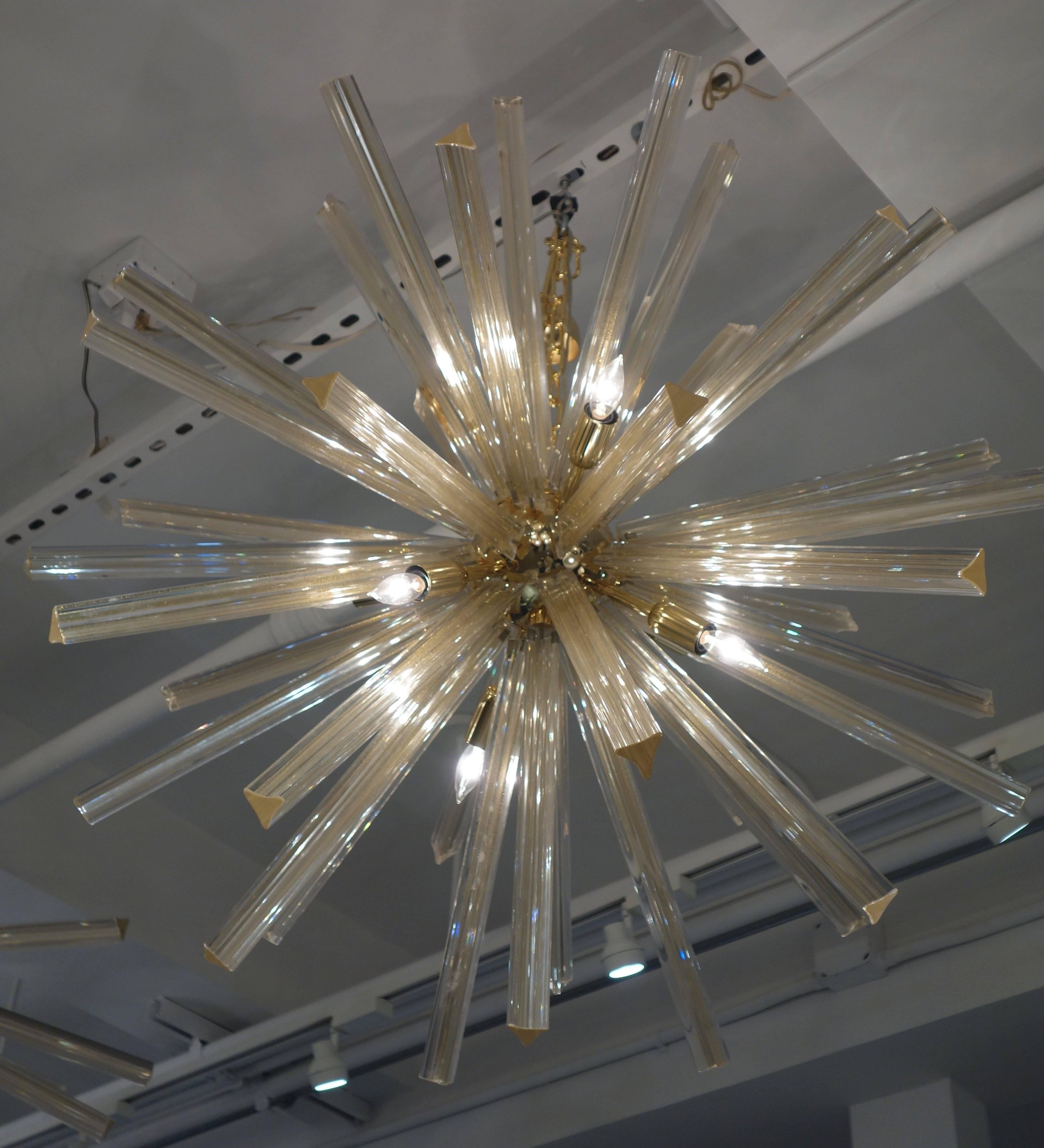 An Italian Murano glass Sputnik chandelier each of the 40, 16 inch long tired spikes of clear hand blown glass infused with real gold dust radiating from a polished brass orb with nine candelabra light sockets wired for the American market suspended