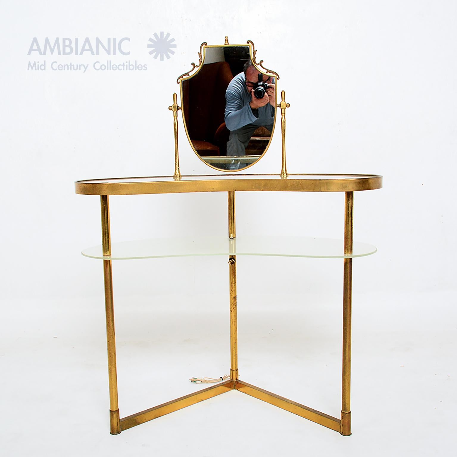 For your consideration: a vintage Italian vanity table in the style of Fontana Arte. Brass frame structure supports the top with glass and glass shelf. The top has an adjustable vanity mirror in a decorative frame.
Mirror can be tilted up or down.