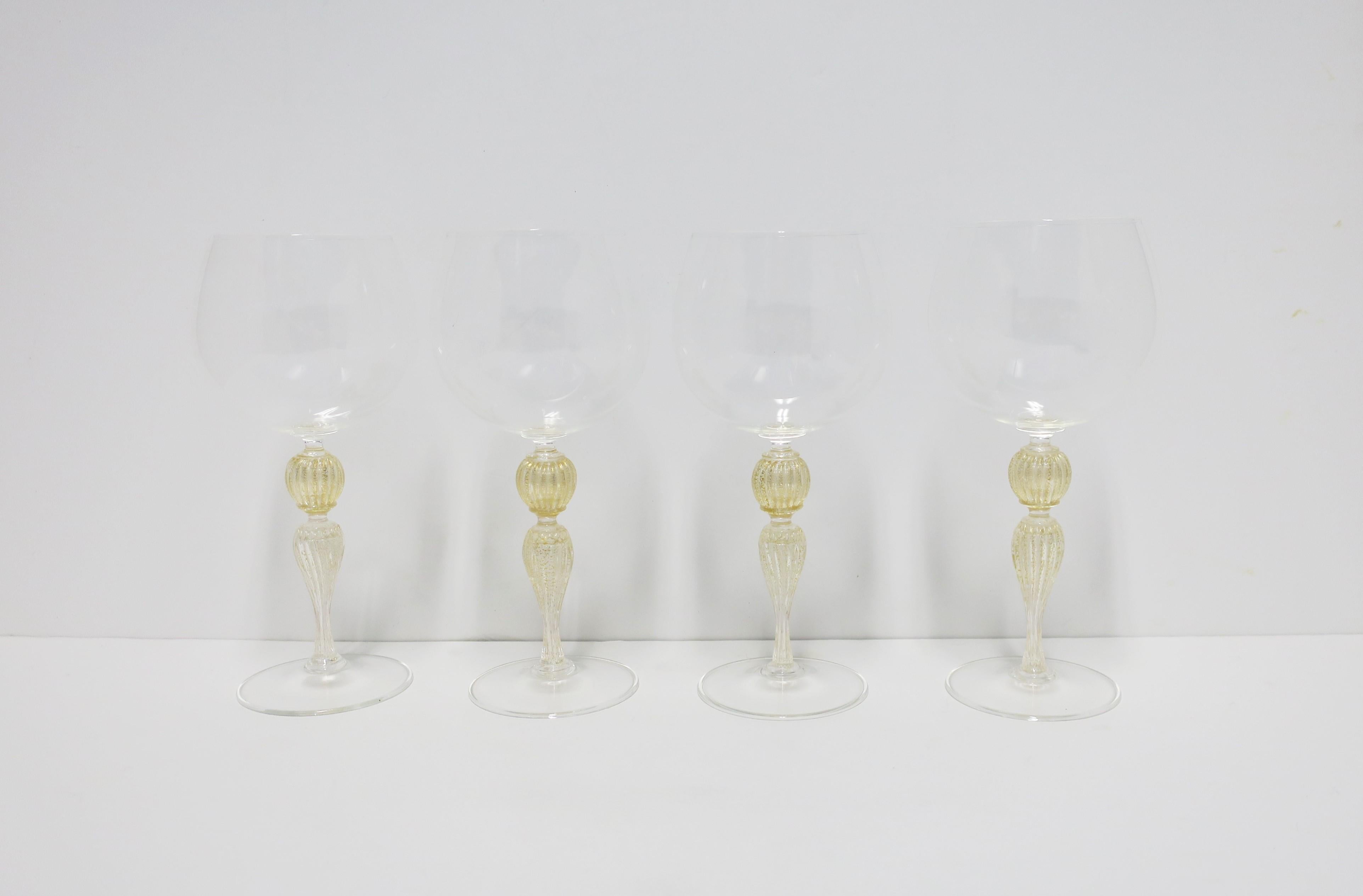 A beautiful set of four (4) Italian Venetian Murano gold and transparent art glass wine goblet glasses by Cenedese, circa late-20th century, Italy. Enjoy white or red wines with these beautiful glasses. Great for any bar, bar cart, entertaining