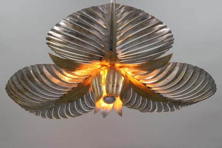 Adorable Hollywood Regency style Italian golden and silver color patinated metal palm leaf ceiling lamp from the 1960s. This impressive ceiling lamp features three backlights, each with a socket for an E14 size light bulb and one central light with