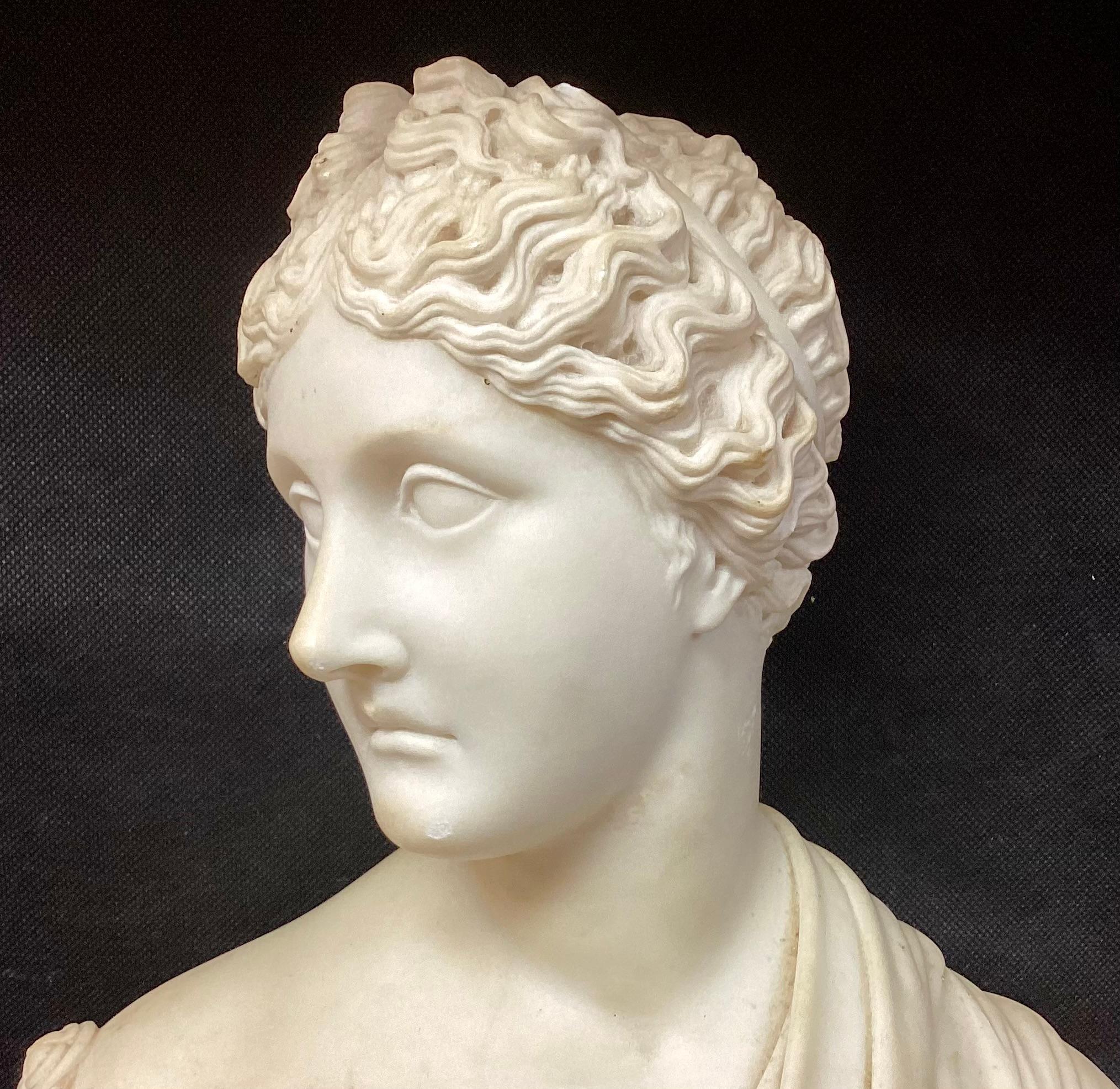Buste de femme en marbre néoclassique italien du 19e siècle, sculpté à la main. Le buste représente la tête et le cou d'une jeune femme sculptée de façon complexe, portant une délicate draperie sur le décolleté. L'expression de son visage est