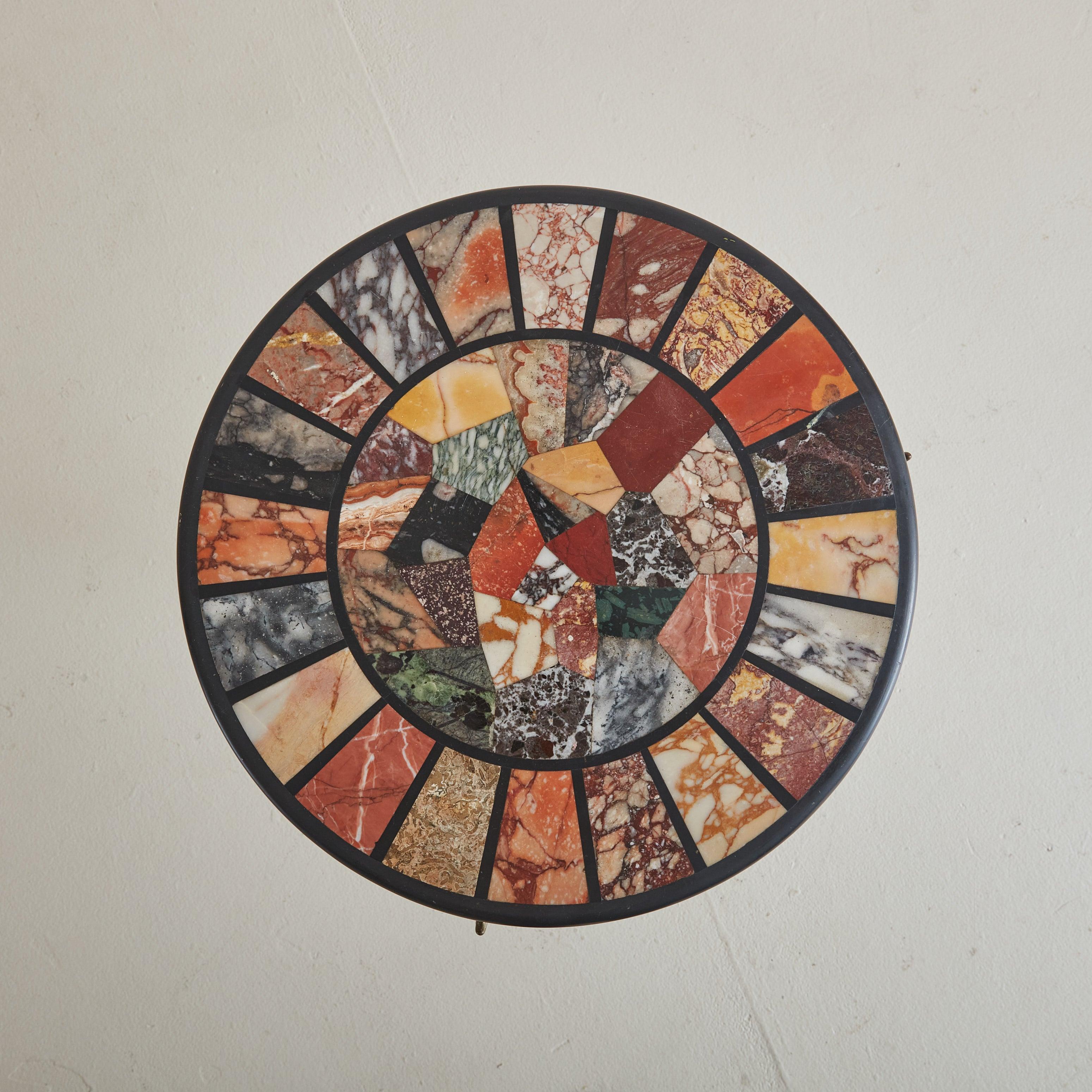 Cette table d'appoint italienne des années 1960 présente un captivant plateau rond incrusté d'une vibrante mosaïque de carreaux de marbre multicolores. Chaque pièce reflète des teintes uniques, se fondant dans un motif qui attire l'attention. Les
