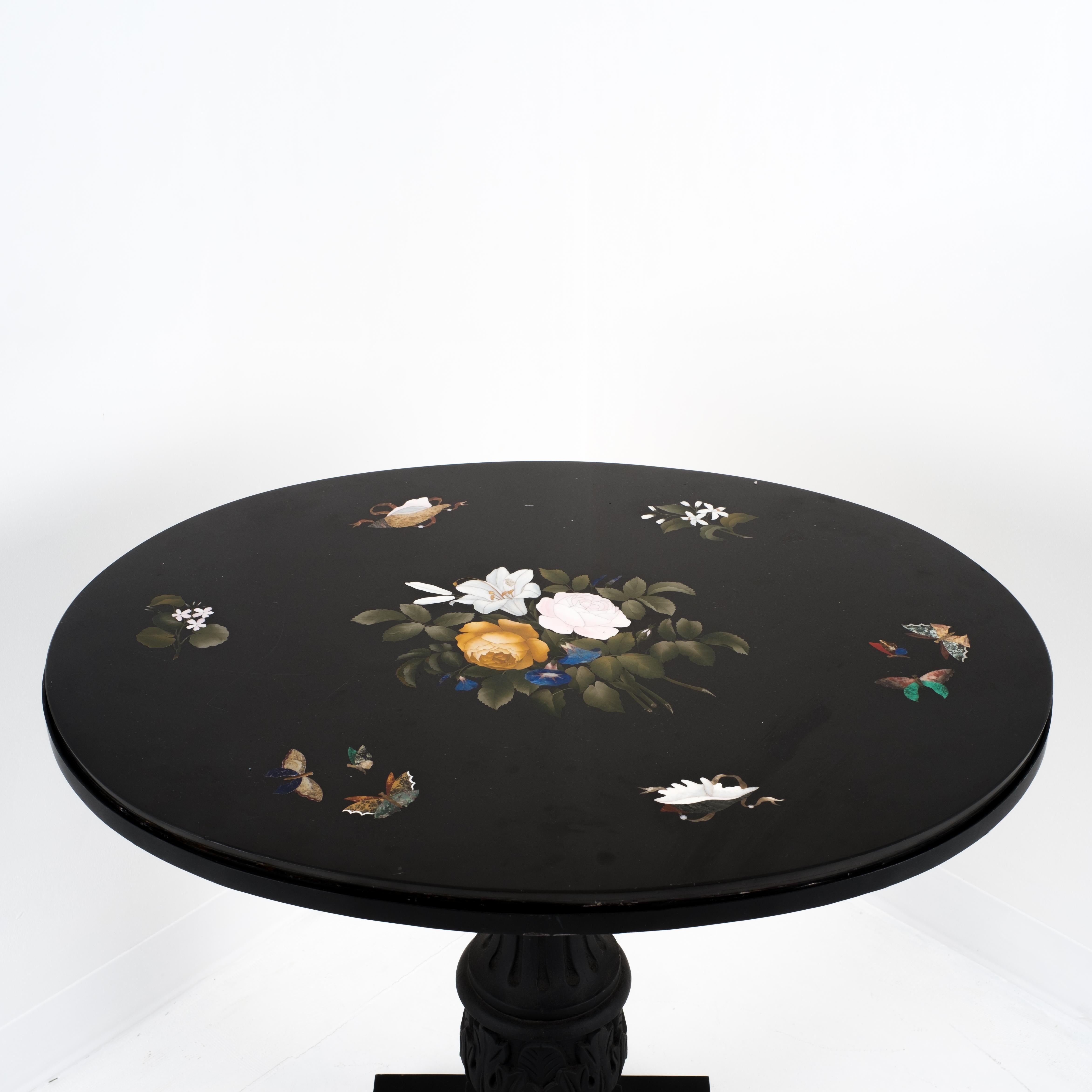 Traditional oval Pietra Dura table top of black marble inlaid with naturally colored stone creating a bouquet of yellow roses with a white oriental lily. Surrounding the central inlay are pairs of inlays spaced equidistantly around the perimeter.