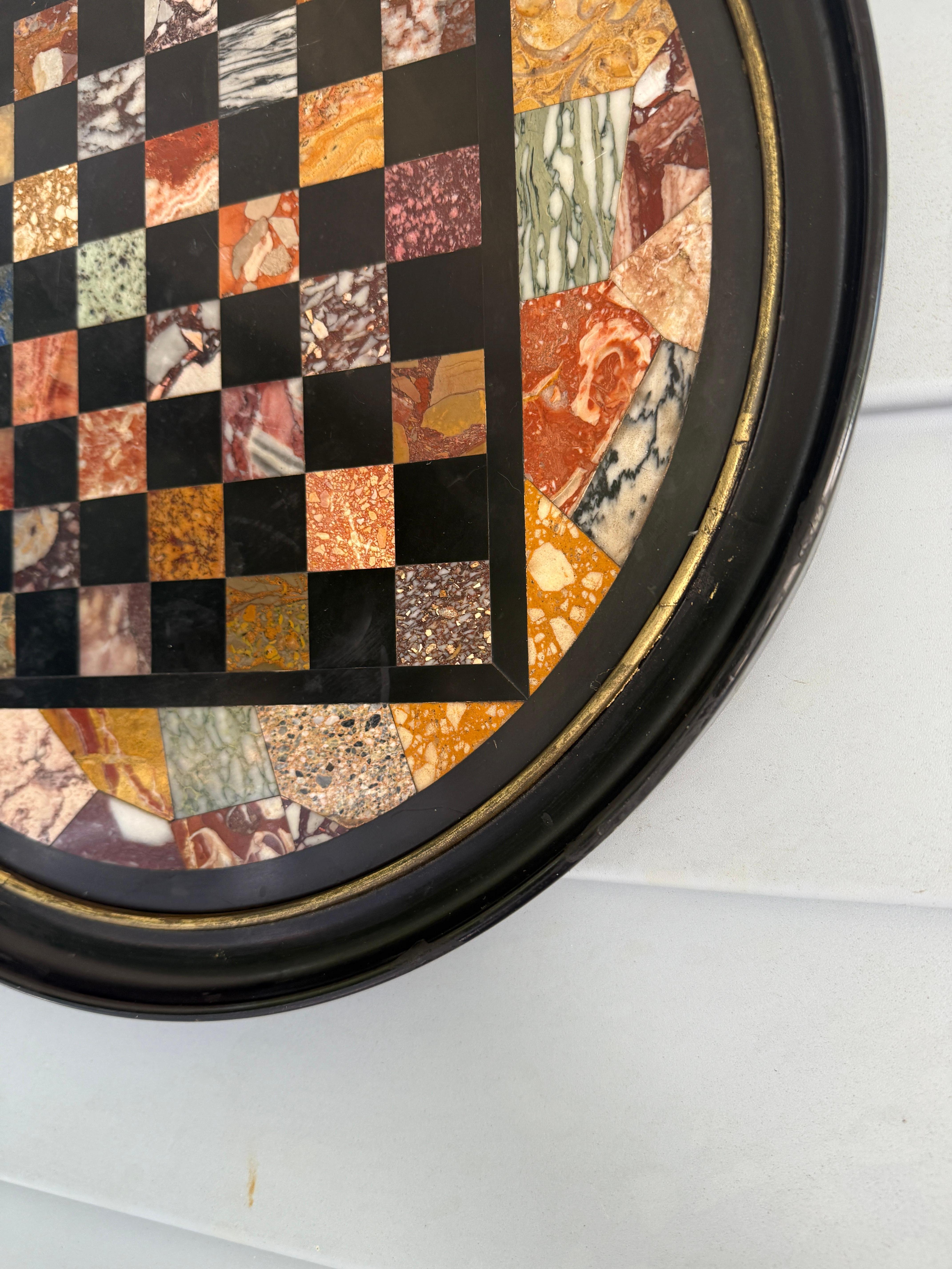 Plaque circulaire en pietra dura finement travaillée, probablement originaire d'Italie au milieu ou à la fin du XIXe siècle, ce spécimen d'échiquier incrusté de marbre et de pierre dure allie virtuosité décorative et traditions de collection