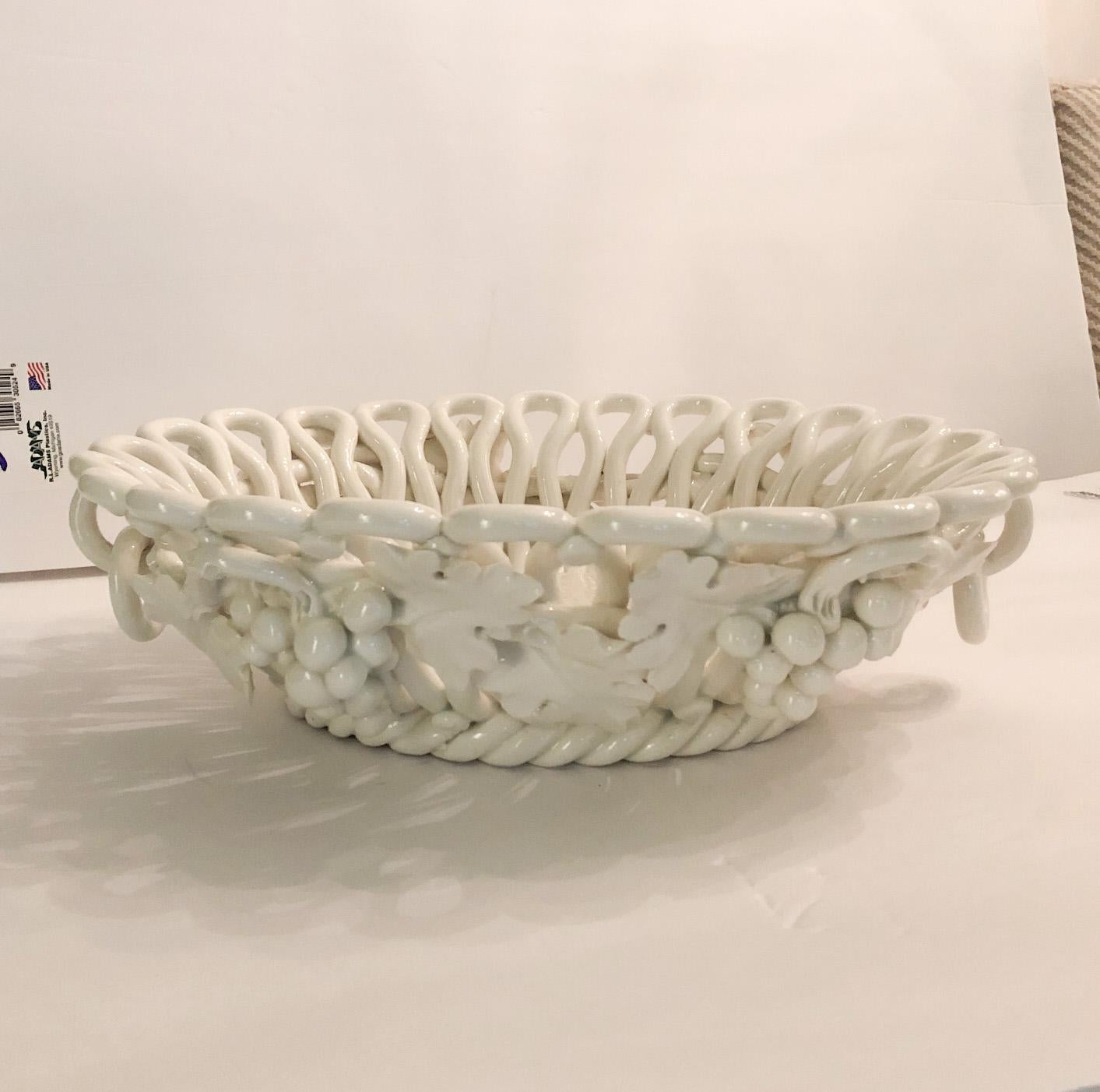 Wonderful large-scale cream ceramic bowl made in Italy. Note the door knocker-style handles which are intact. One grape leaf is broken but is barely visible given its location at top under the rim of the bowl. There is a factory glaze skip on the