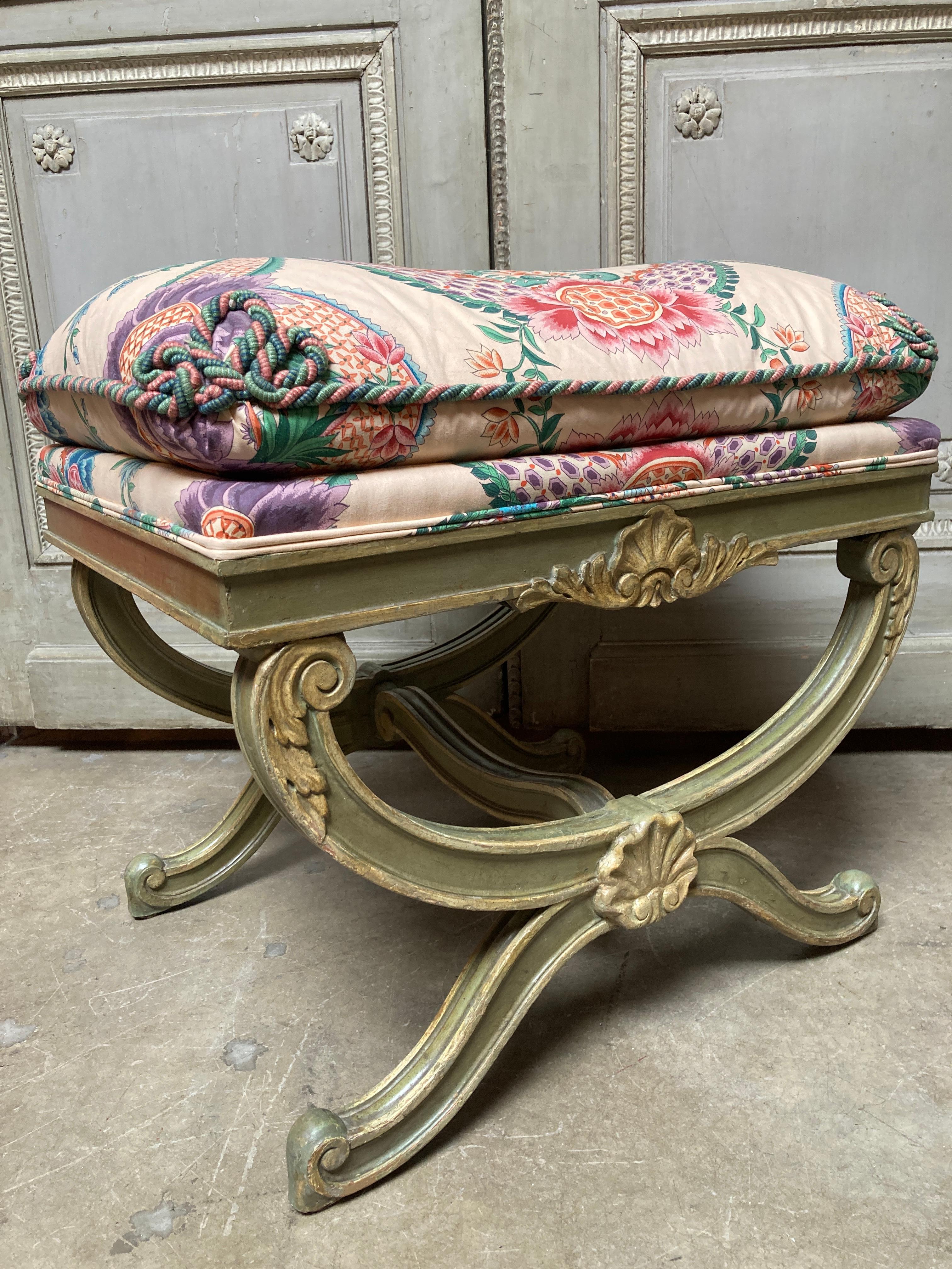 A mid 20th century Italian carved wood stool with a green and great painted finish. The stool is carved with scrolled feet and shells. The fabric is water stained and some of the rope trim is loose.