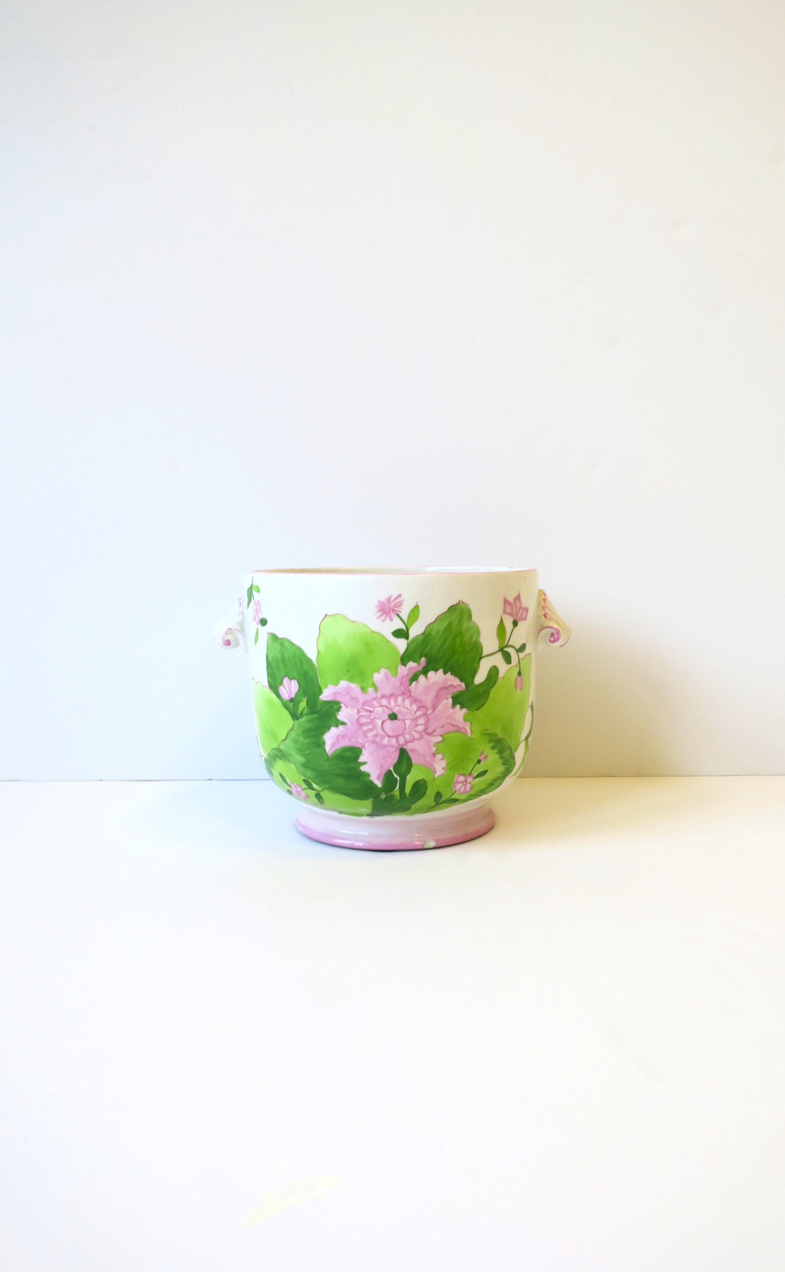 An Italian white ceramic flower or plant cachepot planter jardiniere holder with pink and green flowers and leaves, circa late-20th century, Italy. Piece has a floral design on front and back with scroll handles on sides. Pot has a 'Palm Beach'