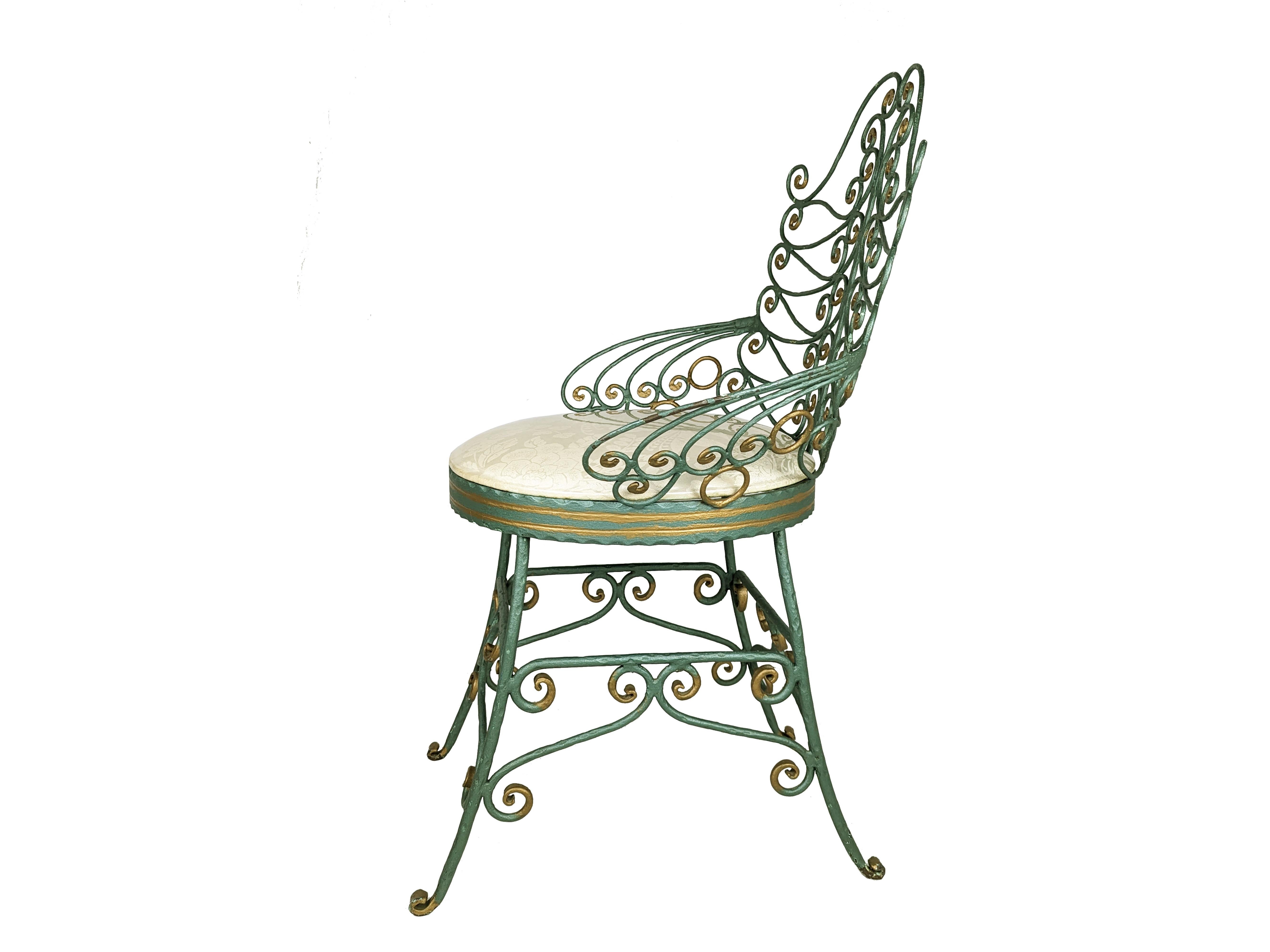 Rare et agréable chaise en fer forgé vraisemblablement du milieu du 20ème siècle. Réalisée dans le style des chaises paon avec un dessin complexe de volutes denses. La chaise est de couleur verte avec des détails décoratifs dorés. L'assise,