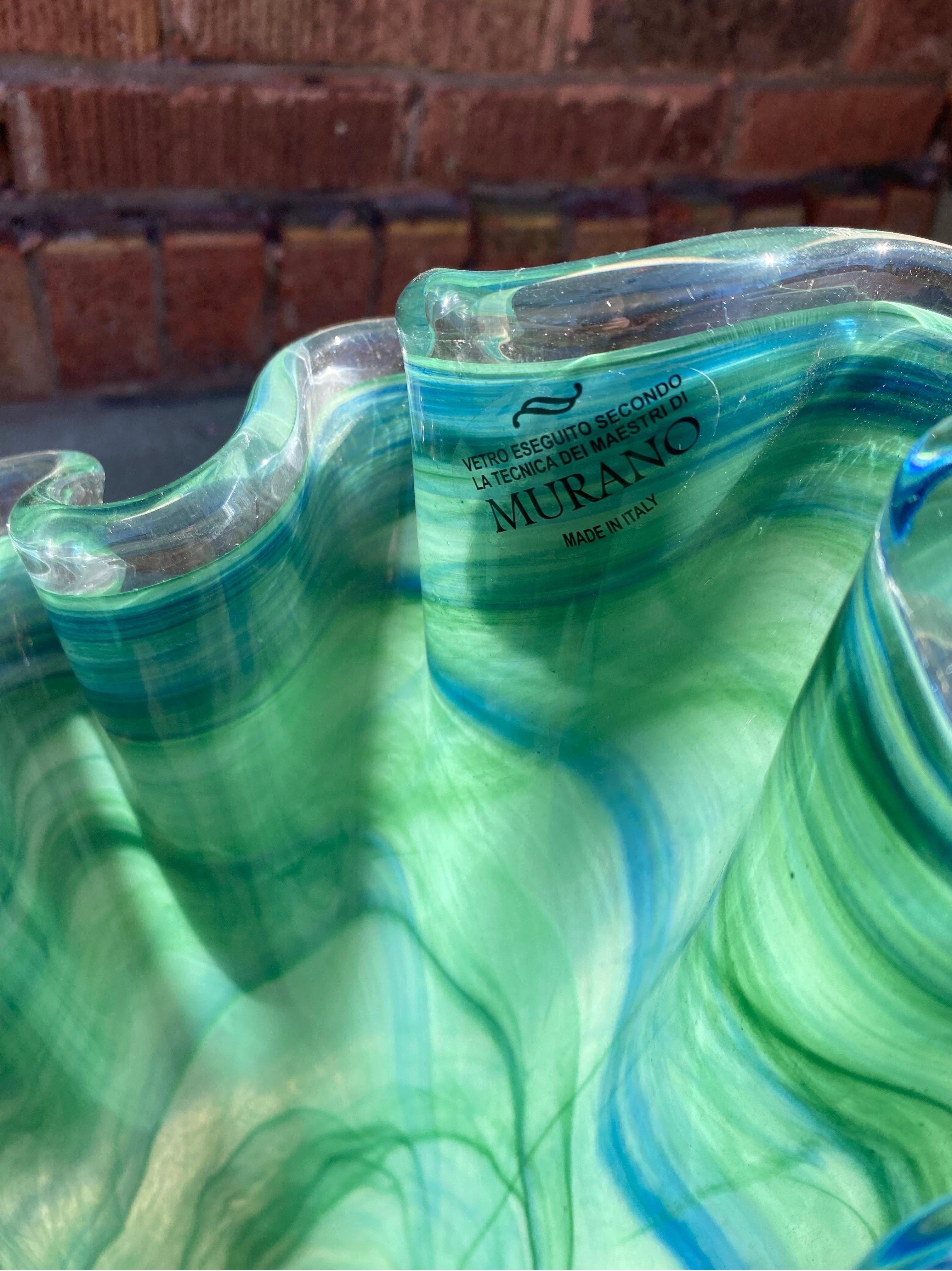 Vase vintage italien en verre de Murano vert 

Ce vase en verre ondulé présente des stries de bleu et de vert foncé sur un champ de couleur vert pâle. Il contient une étiquette de fabricant pour Murano.

Circa Mid 20th Century

H 16