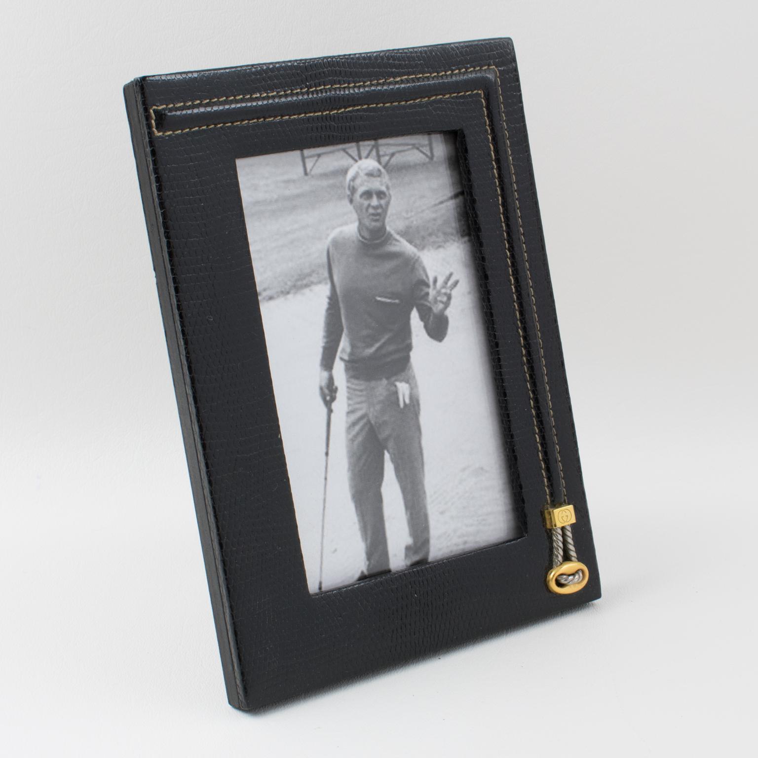 Superb picture photo frame by Italian designer Gucci. Timeless and elegant black leather with textured pattern ornate with handstitched asymmetric decor. Chrome and brass buckle on the side with engraved Gucci brand logo. Back and easel in black