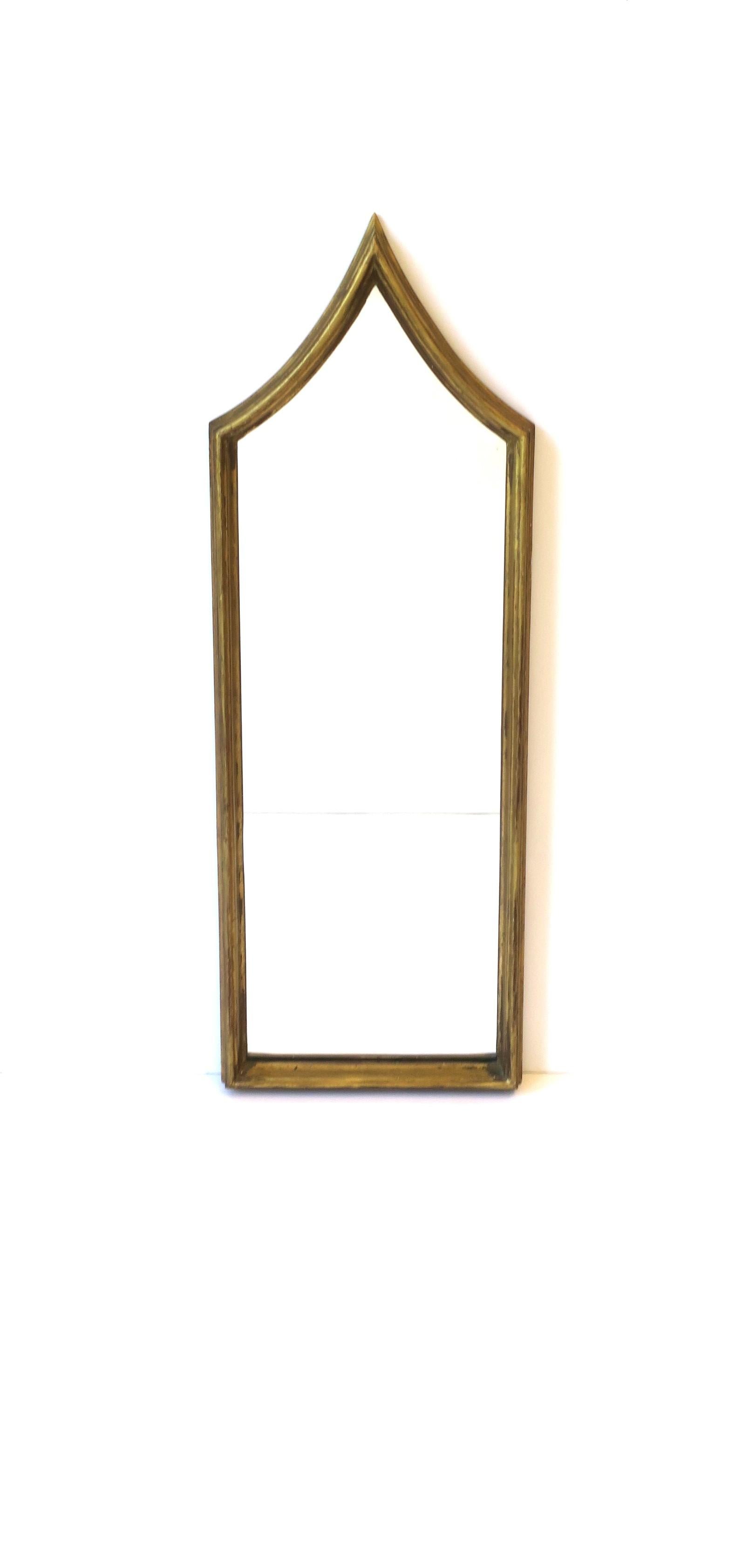 A tall slender Italian mirror with a gold giltwood frame in the Gothic design style, circa early to mid-20th century, Italy. A great mirror for a vanity, hall, foyer, etc., where a tall slender mirror is needed. Mirror shown with Champagne glass for