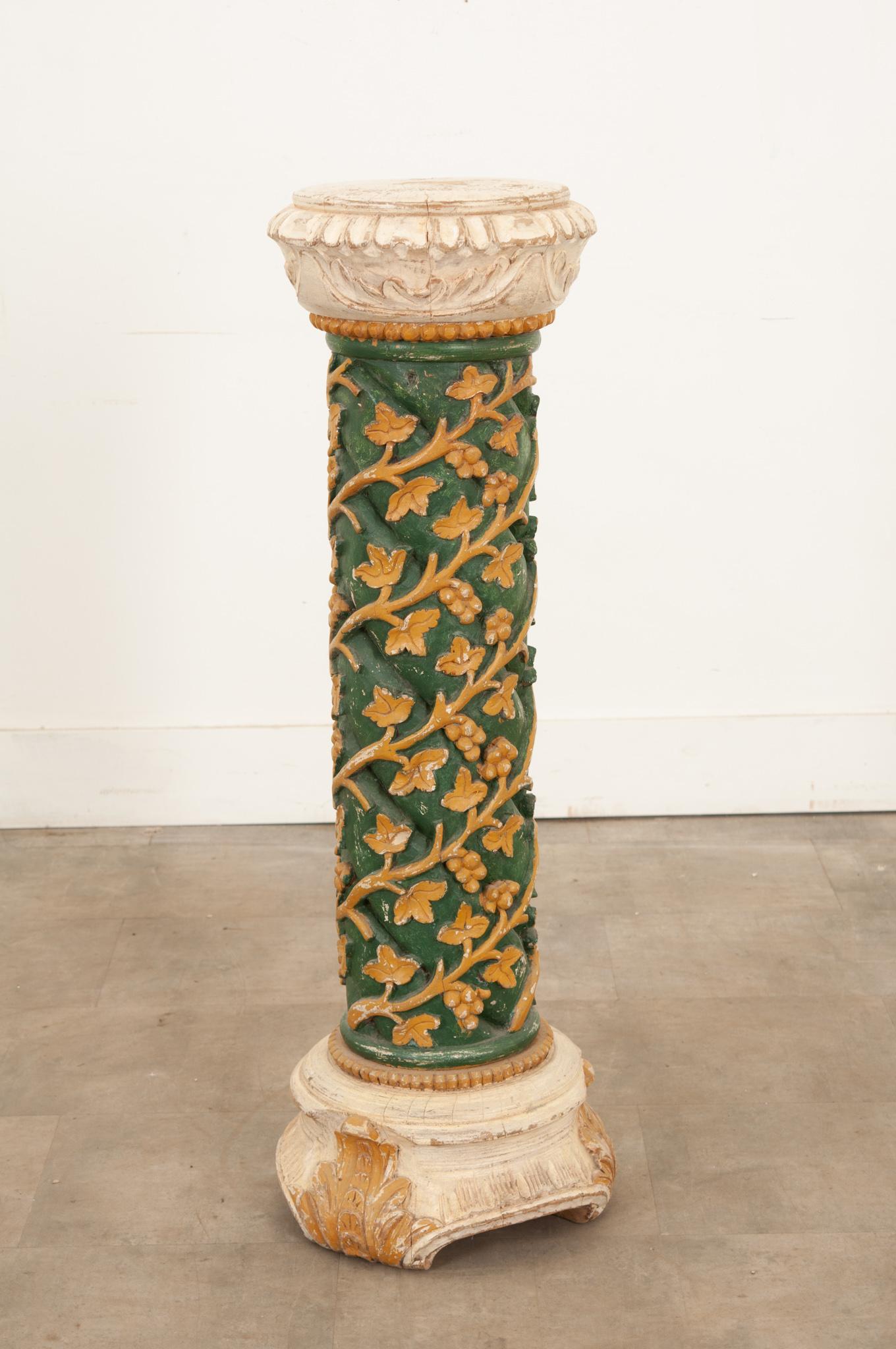 A highly decorative antique pedestal column hand-carved from solid wood with twisting garland detailing and beautiful colors throughout. Elaborately hand-carved out of a large piece of solid wood, this column impresses with a fantastic design.
