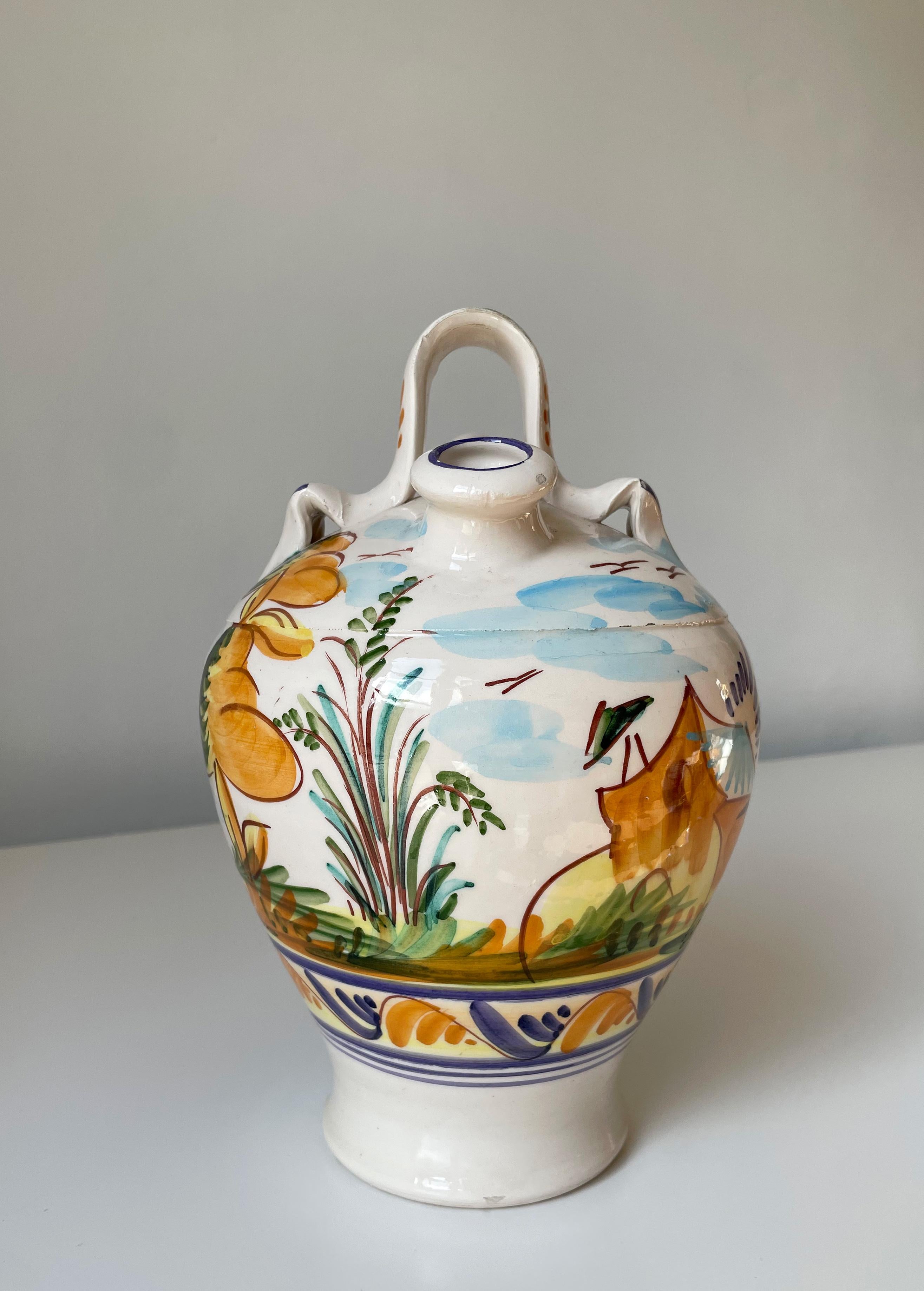 Italian ceramic pitcher bottle vase with organic floral landscape decorations. Hand-painted yellow, orange, green, blue and brown coloured motifs under clear glaze. Handle on the top and two openings - one very narrow, the other opening 2.5 cm/1