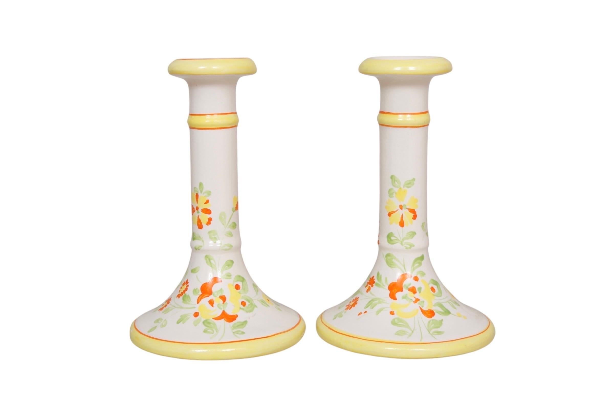 Un par de portavelas de cerámica de color hueso. Brillantemente decorada con flores pintadas a mano en naranja y amarillo. Fabricado en Italia para Mill Pond House. Dimensiones por candelabro.