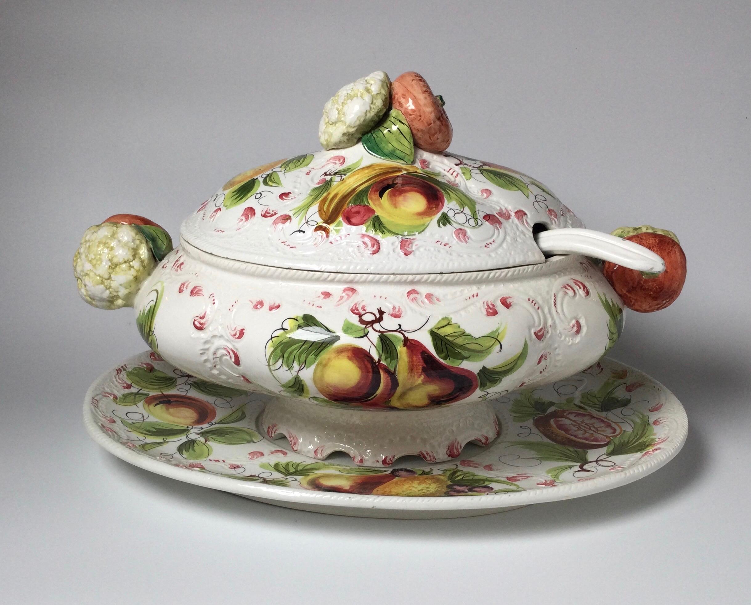 Vibrant hand painted soup or stew tureen with original ladle and underplate. The tureen with hand painted vegetable decoration on the body and handles. Displays beautifully. Platter measures 17 wide, 12 deep, total height is 11.5.