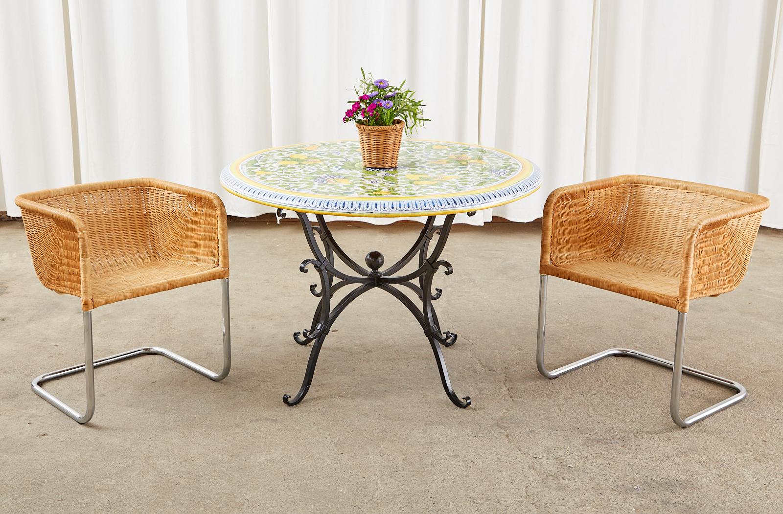 Gorgeous Italian pottery patio garden dining table featuring a round glazed, hand-painted top. The Mediterranean themed table is embellished with white pomegranates and Amalfi yellow lemons over a white ground. There are grape clusters and scrolling