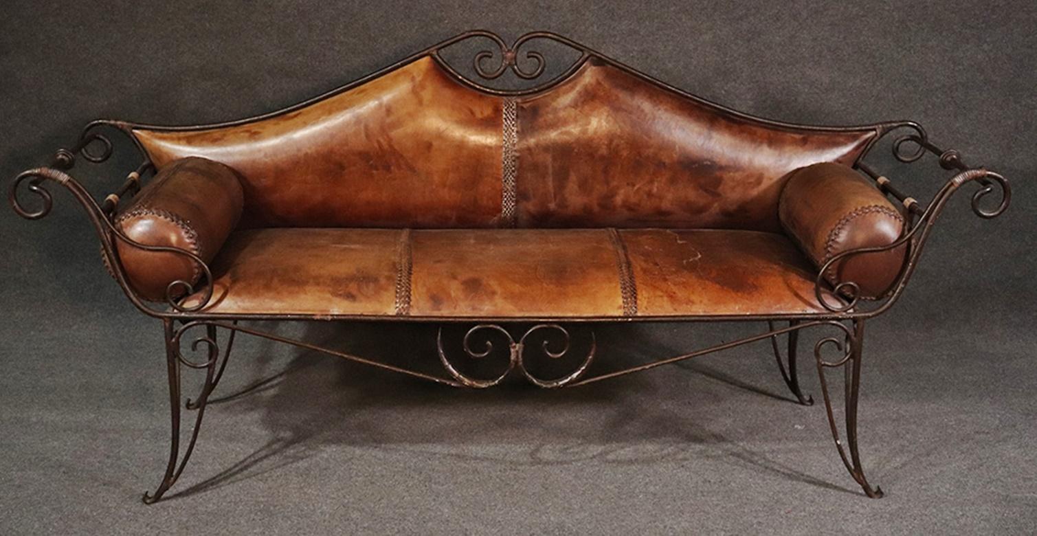 This handwrought iron Italian made bench features wonderful antique distressed leather and dates to the 1920s era. The leather is antique and time worn.