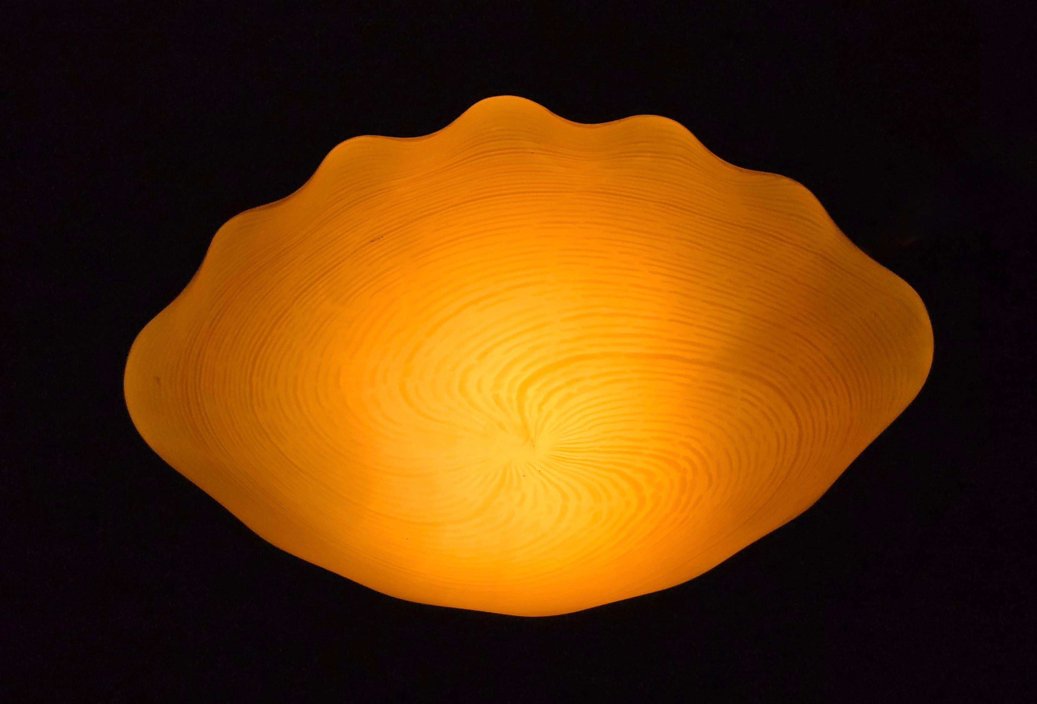 Empotrable italiano de los años 60, soplado a mano, de vidrio opalino cremoso con contorno ondulado en forma de concha y finos dibujos concéntricos. Equipada con dos tomas E14 y la placa de montaje metálica original. Una refinada pieza de cristal de