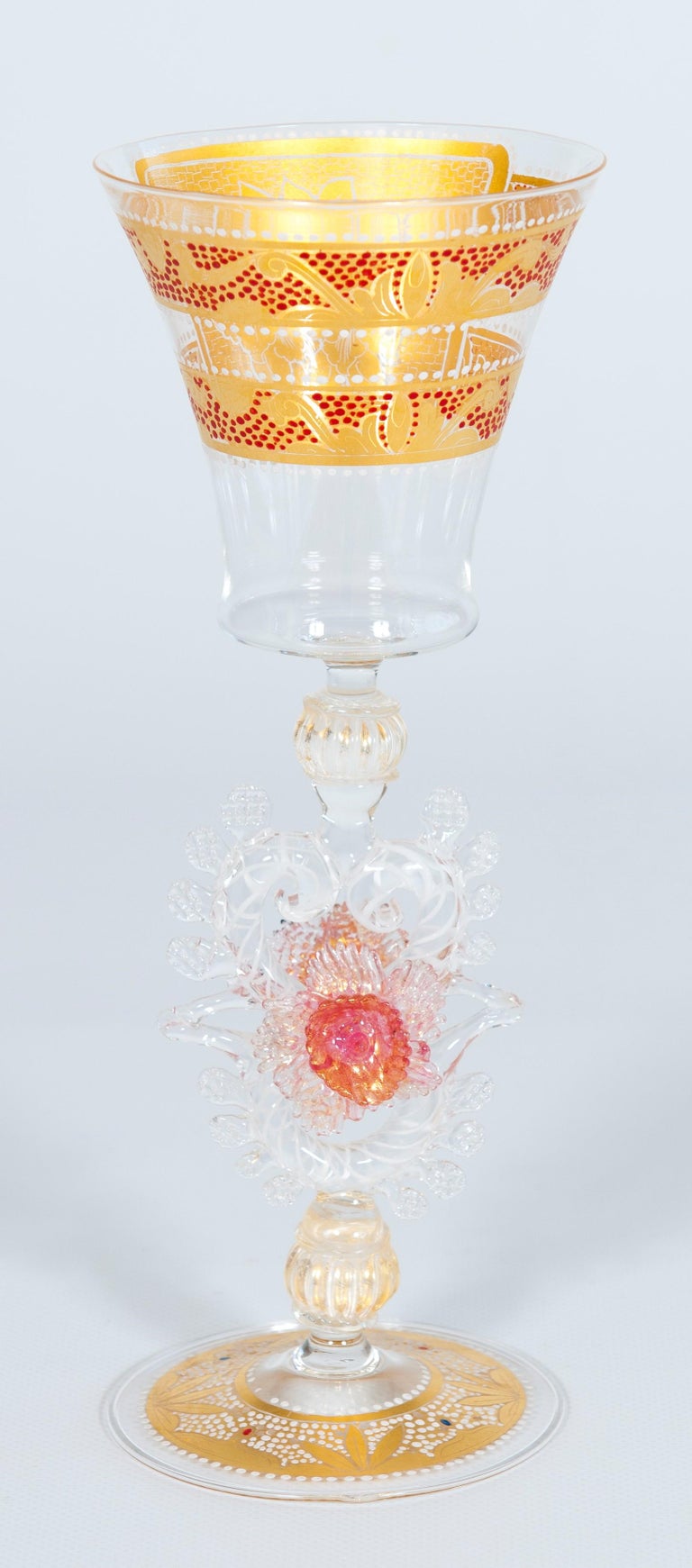 Italian handcrafted chalice in blown Murano glass clear color and gold, 1980s
This elegant chalice is rich in lovely details that add harmoniously to its grace. The stem is richly adorned with different Morise decorations, among which two pink