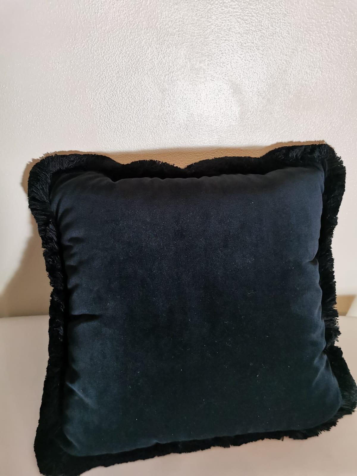 Un cuscino in velluto e poliestere con rifiniture nere della collezione 