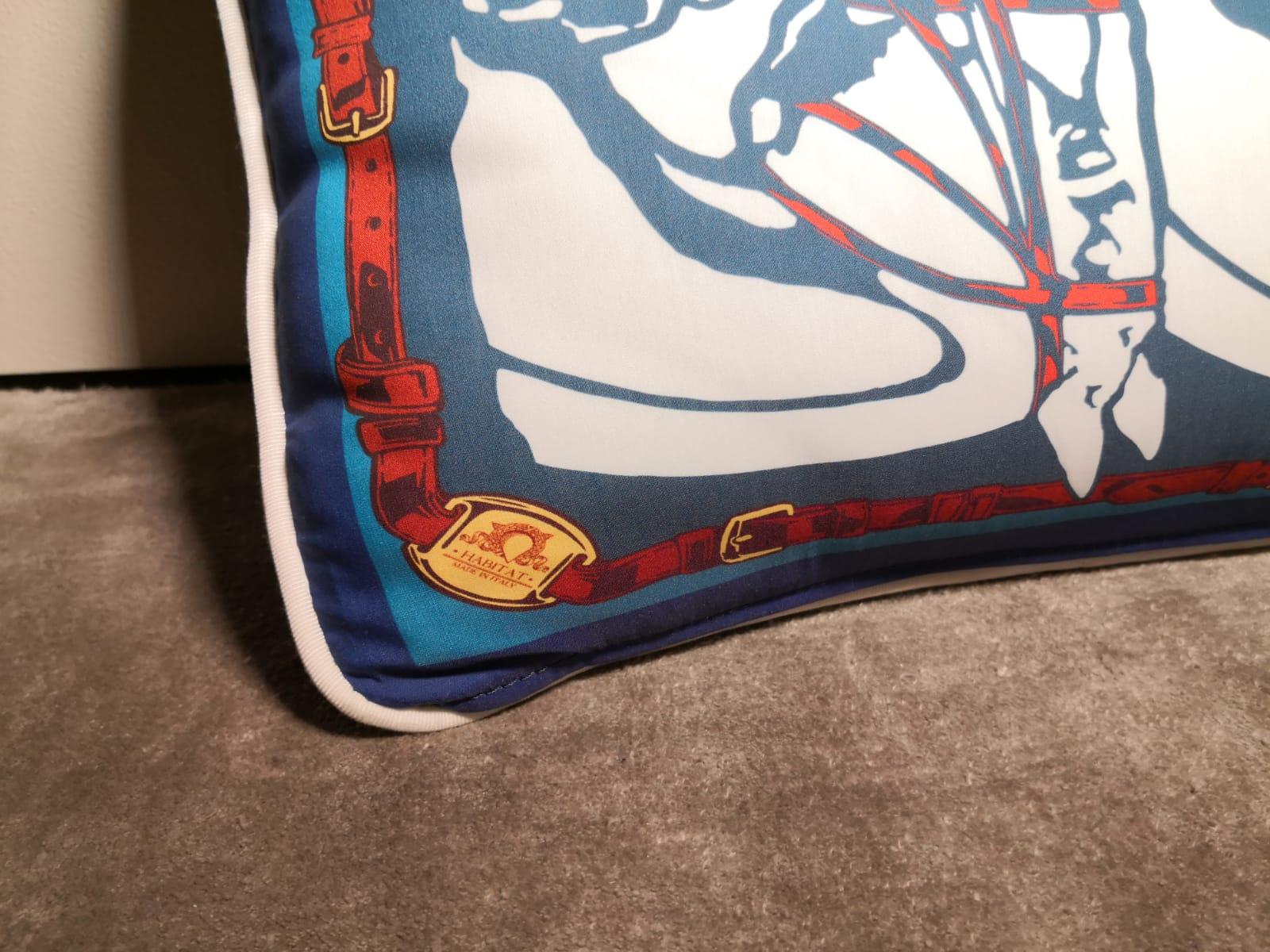 A polyester and velvet (on the back) pillow showing a contemporary horse heads with horesebit an belts. The main colors are blu and red. It's available in other colors, which you can see in our main board.
This pillow comes out as a set of four but