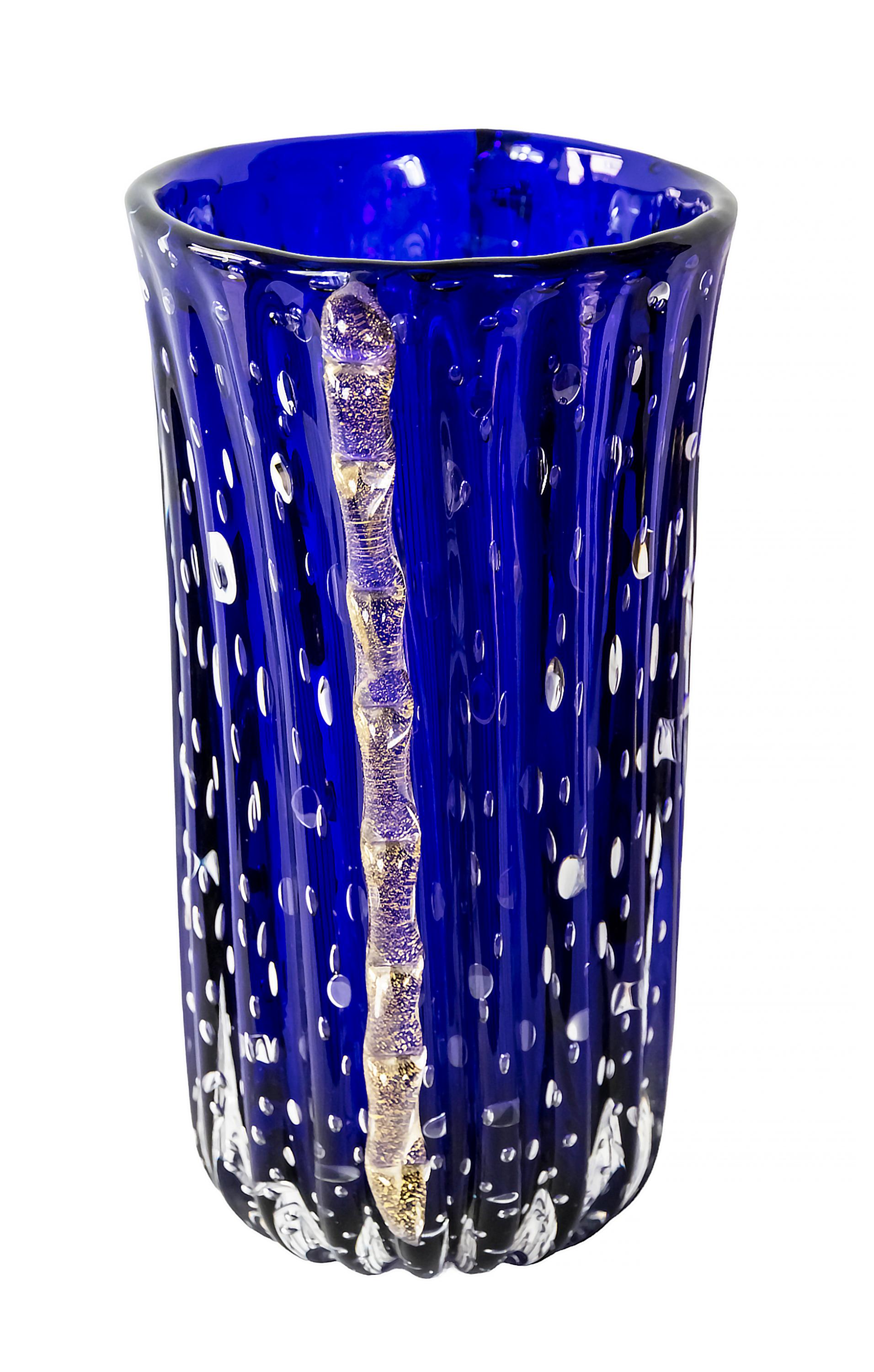 Vase italien en verre de Murano fait à la main vers les années 1970.
Le verre est d'un bleu profond avec des bulles d'air à l'intérieur.
Les côtés sont décorés de détails en verre incrusté de poussière d'or.